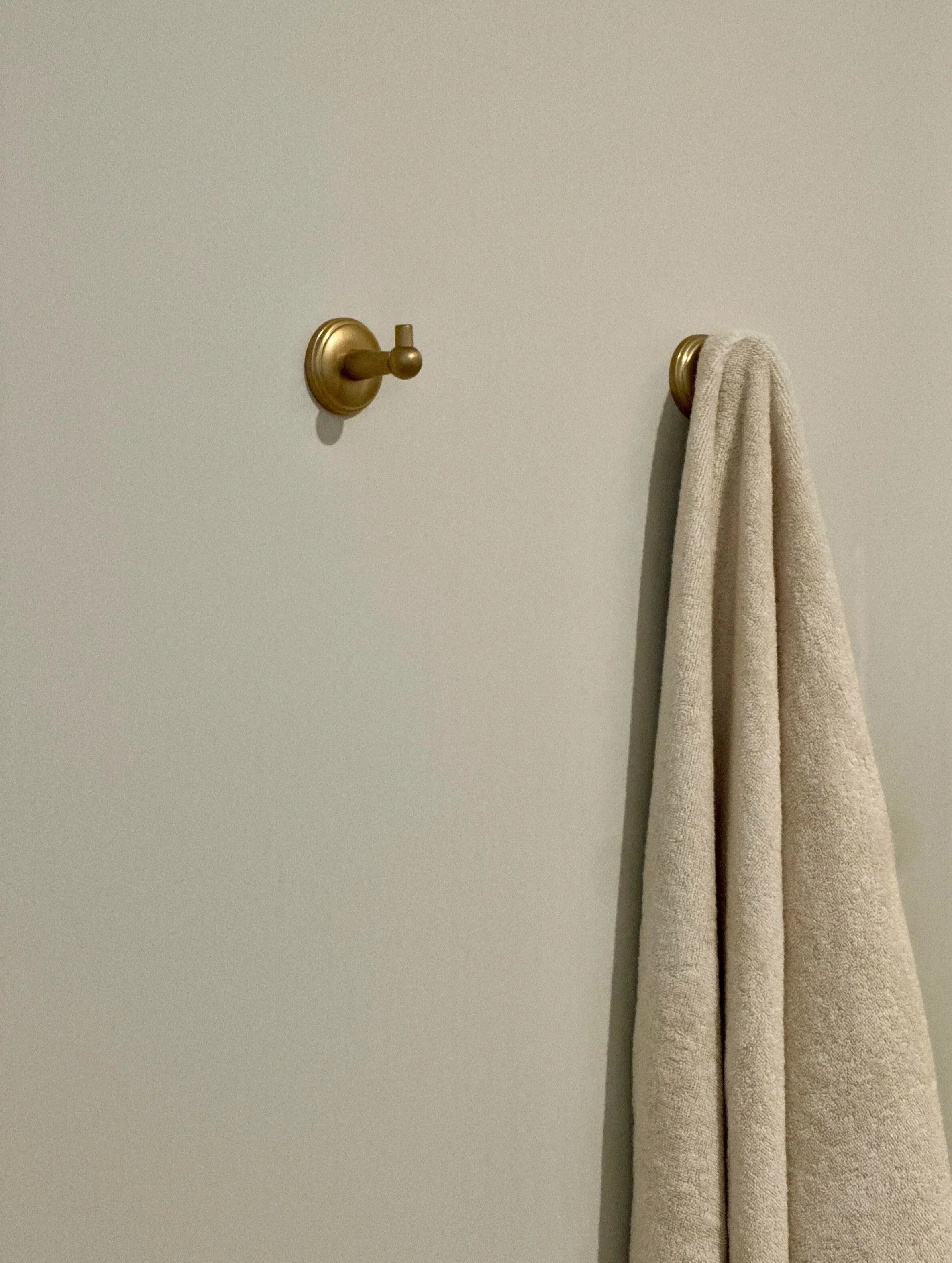 Détail des patères en laiton brossé et des serviettes, assorties aux boutons du placard sur mesure