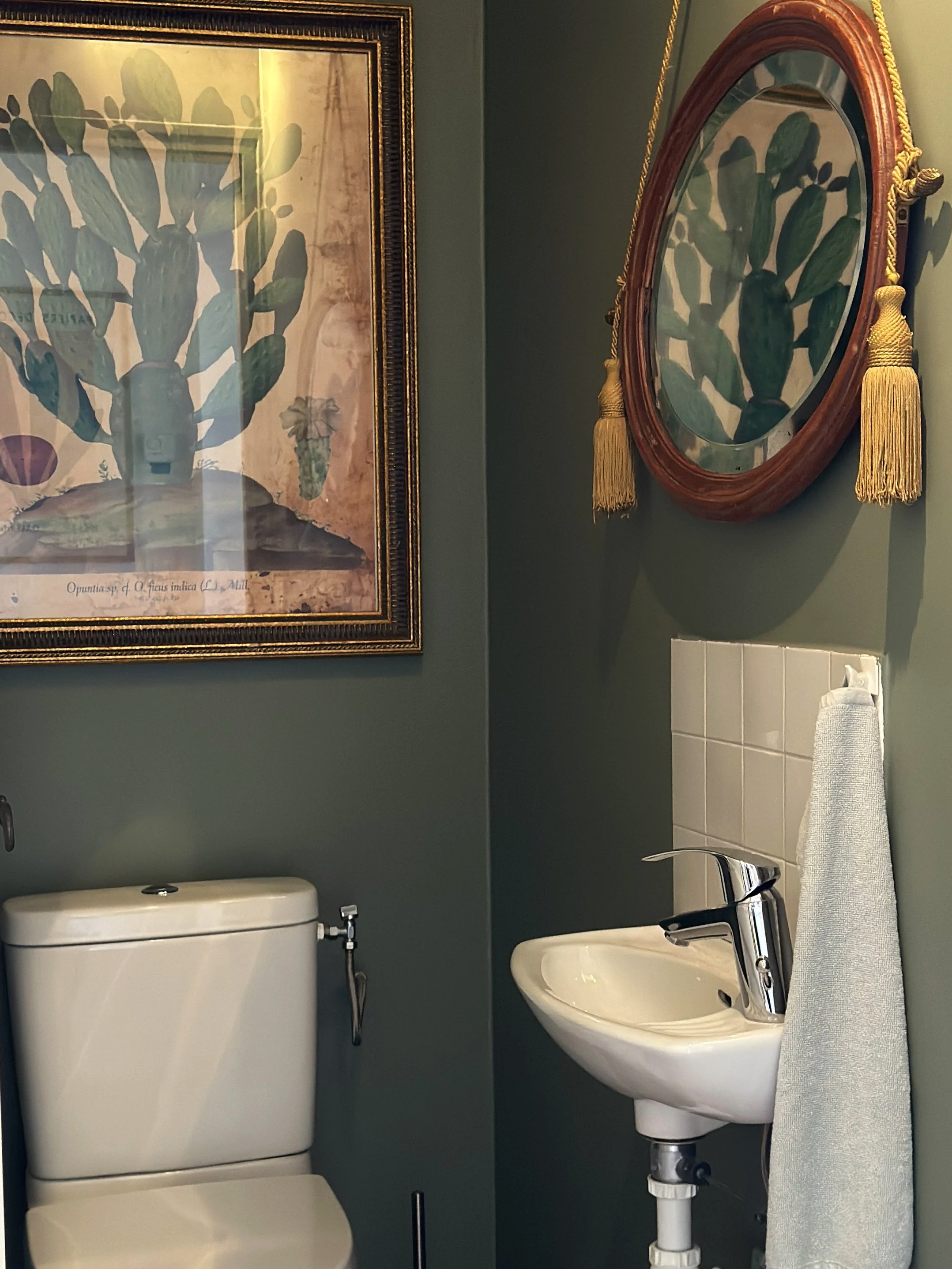 WC des invités : murs vert profond, lavabo ancien et cadres dorés chinés