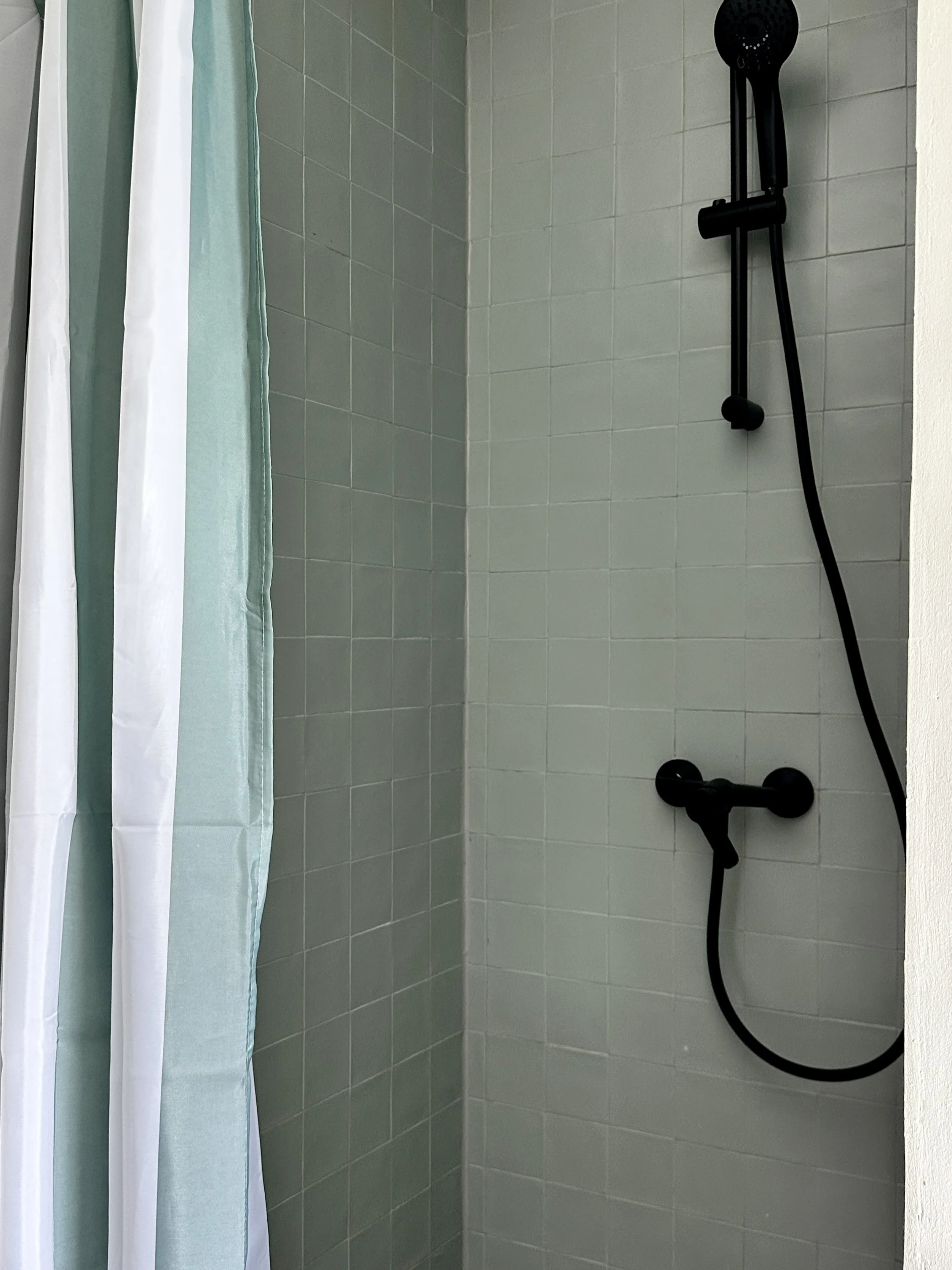 Built-in shower finished with pale green tiles.