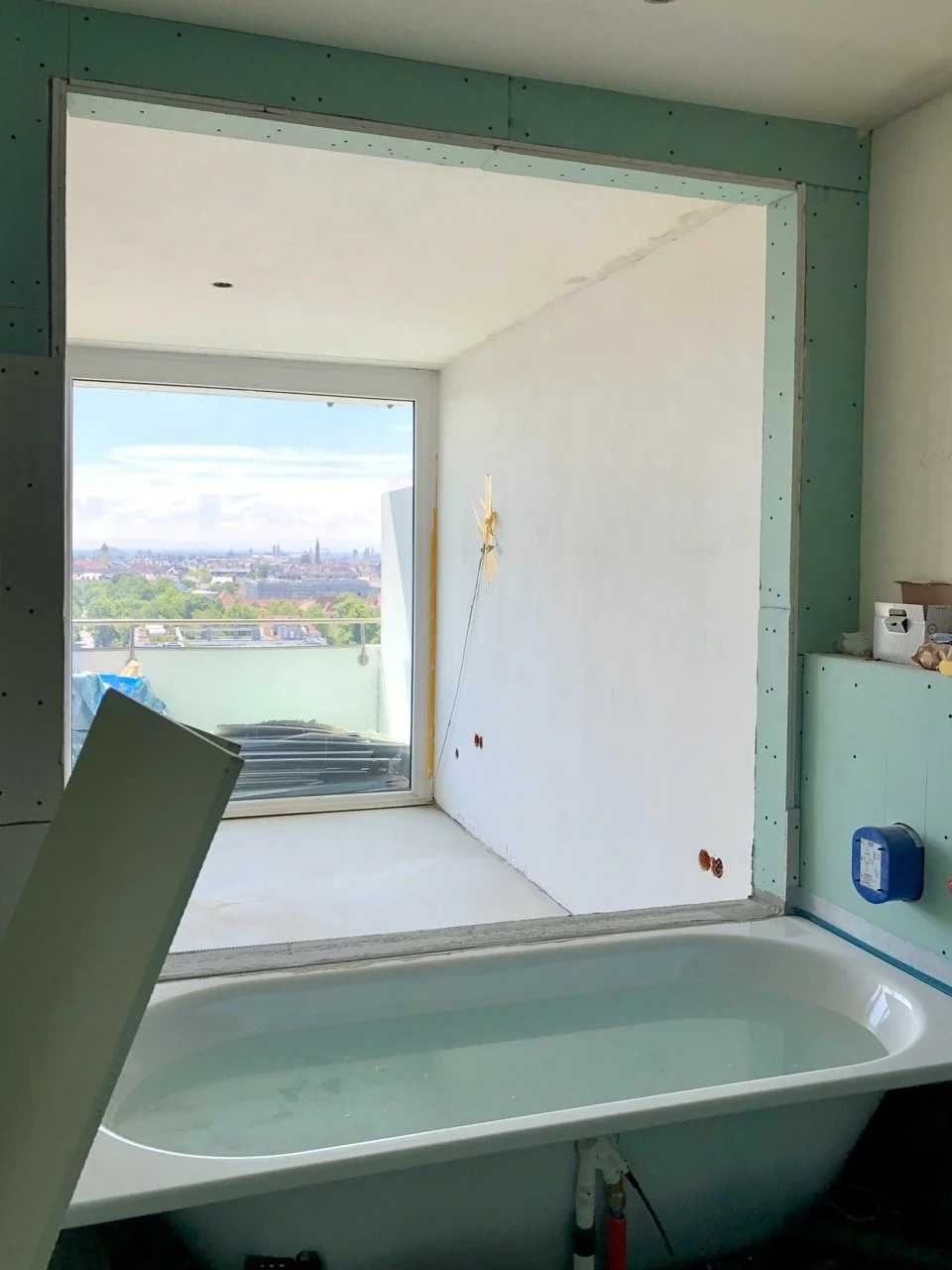 Chantier de la salle de bain : baignoire posée devant l'ouverture qui cadre la vue sur Munich