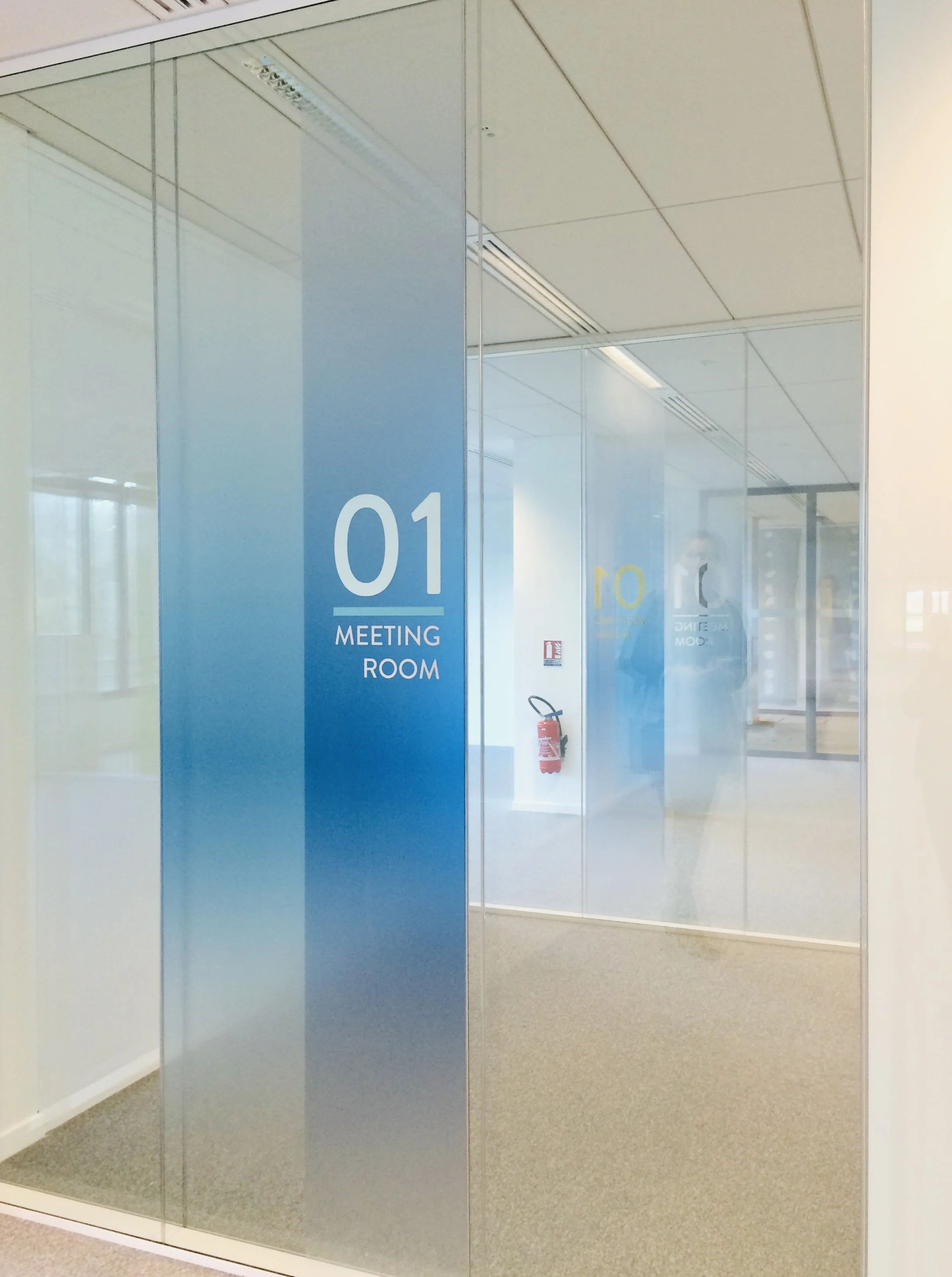 Cloison vitrée avec signalétique dégradée bleue « 01 Meeting Room », bureaux de l'OCDE à Boulogne-Billancourt, design Bea Bühler
