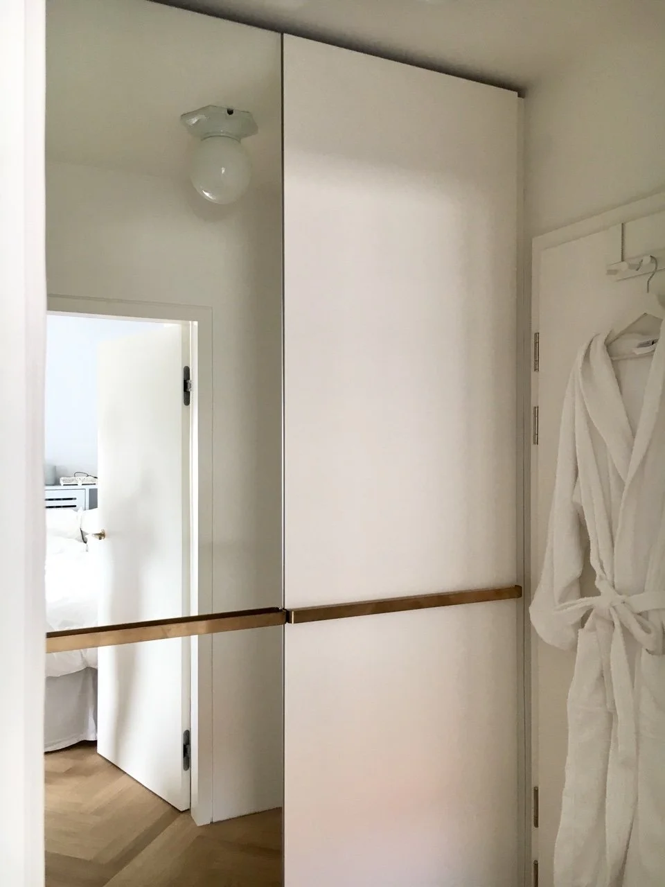 Entrée : grand placard à façade miroir dissimulant un vaste rangement avec lave-linge intégré