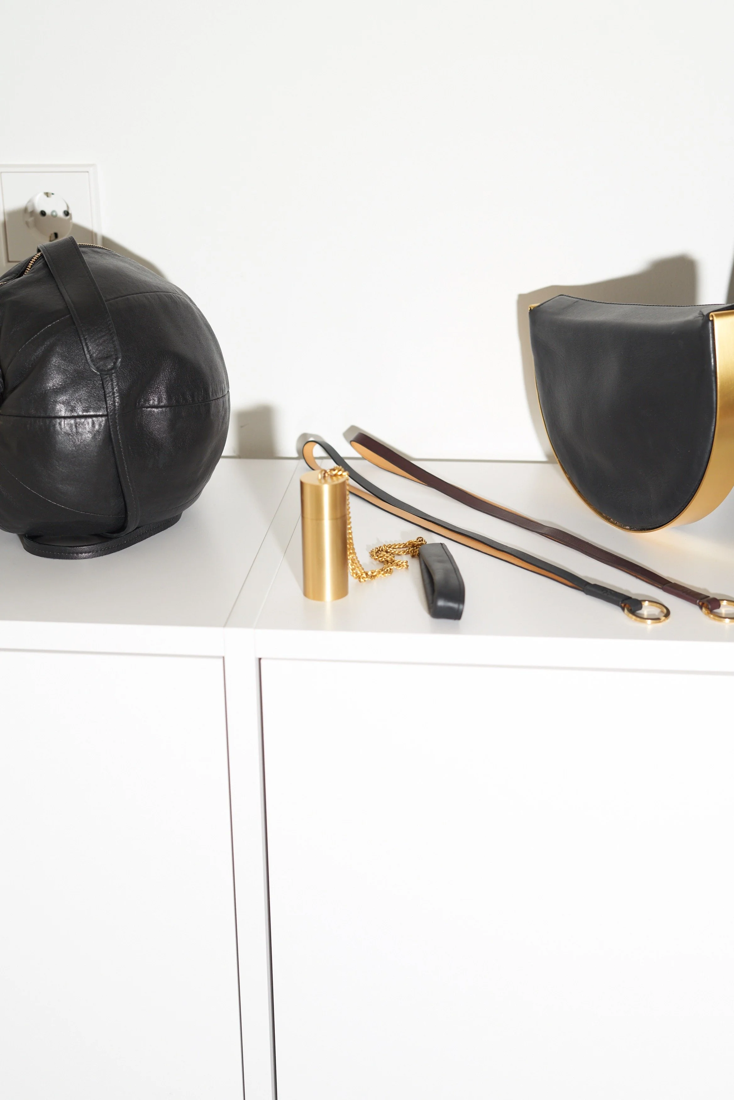 Sac Balloon en cuir noir et accessoires en laiton posés sur les rangements intégrés de l'atelier-boutique