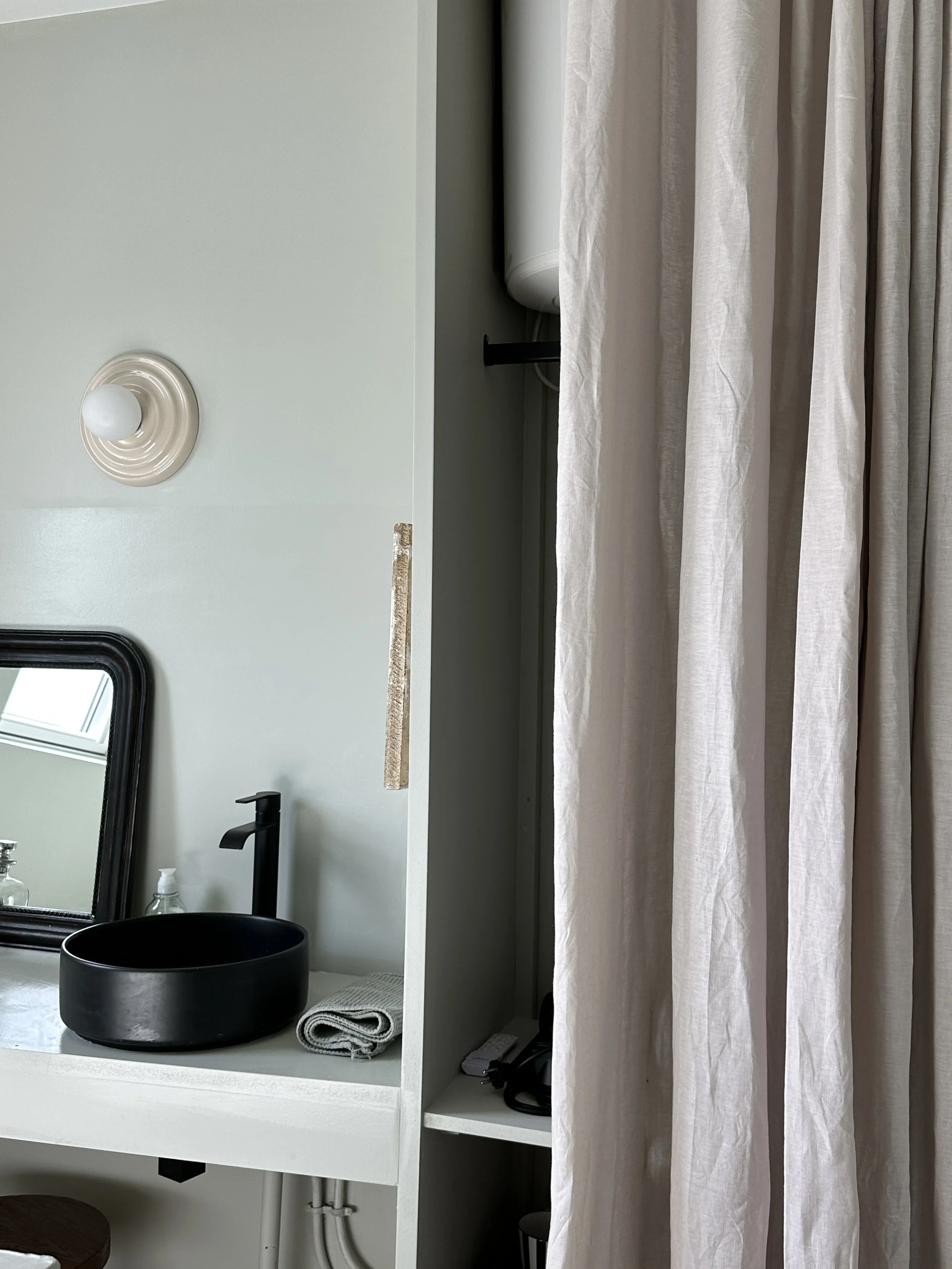 Curtain concealing the sink and storage area.