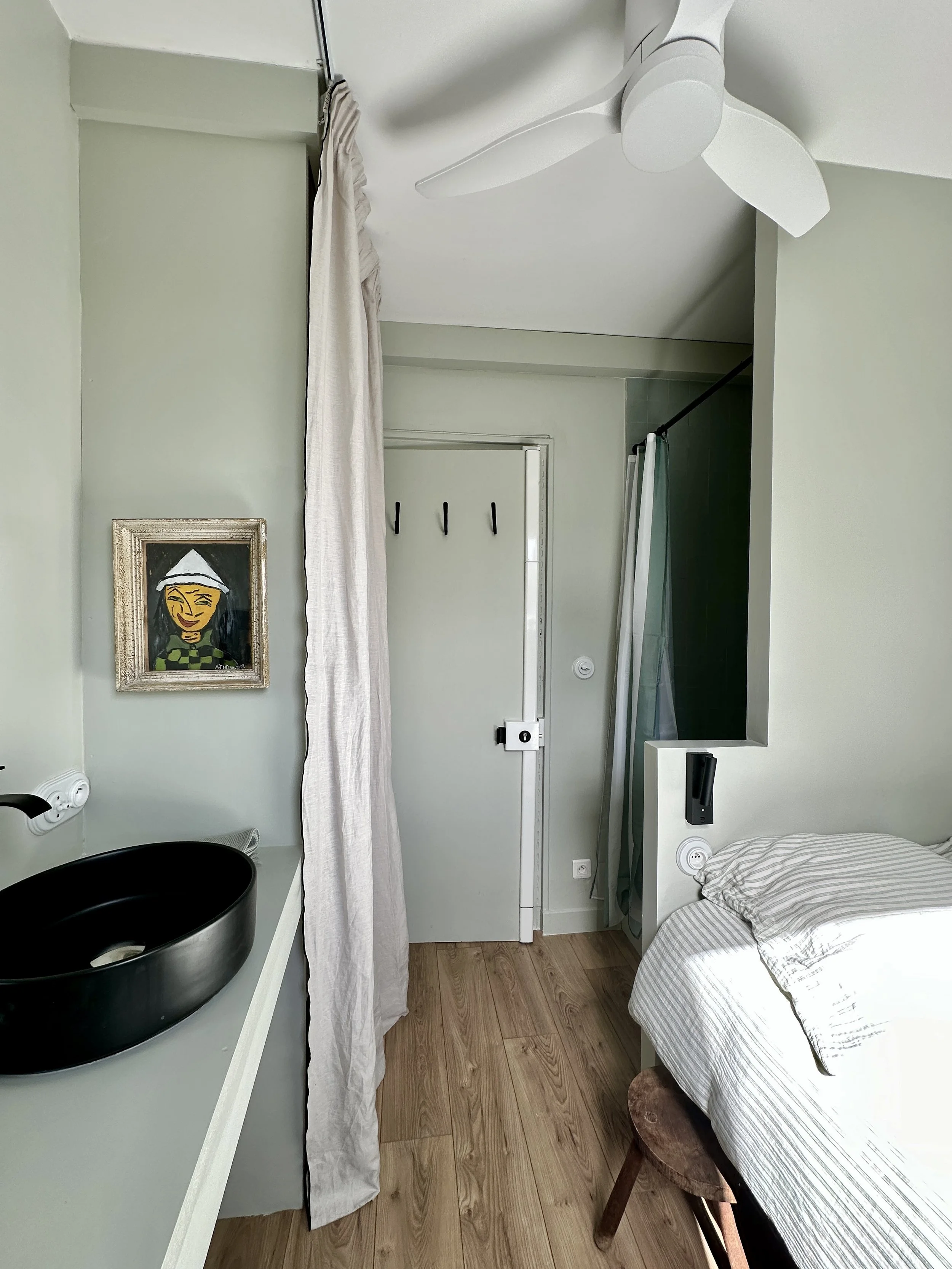 Ceiling fan and linen curtain in a renovated small studio.