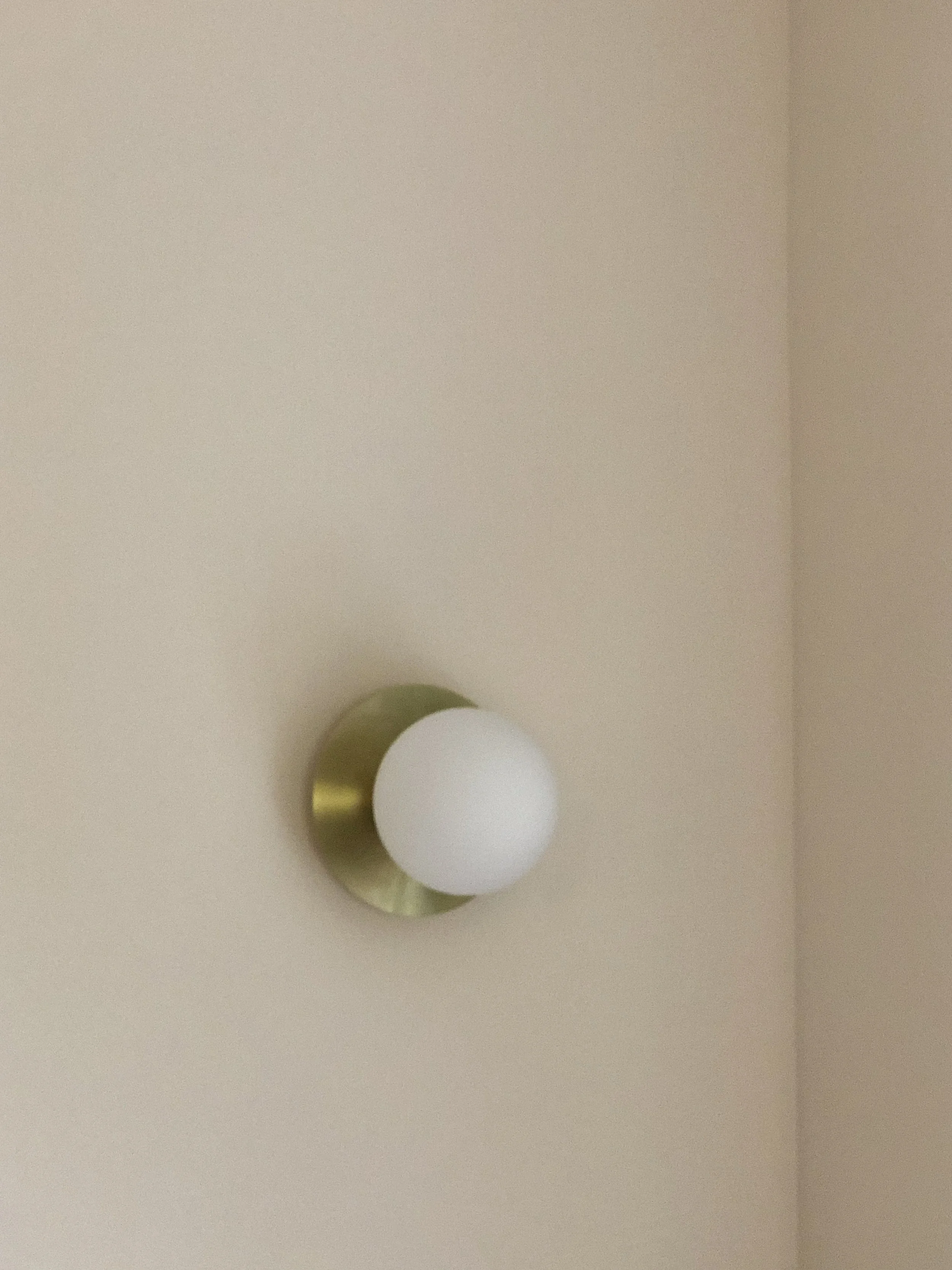 Applique globe en verre et laiton, détail de l'éclairage choisi pour l'appartement
