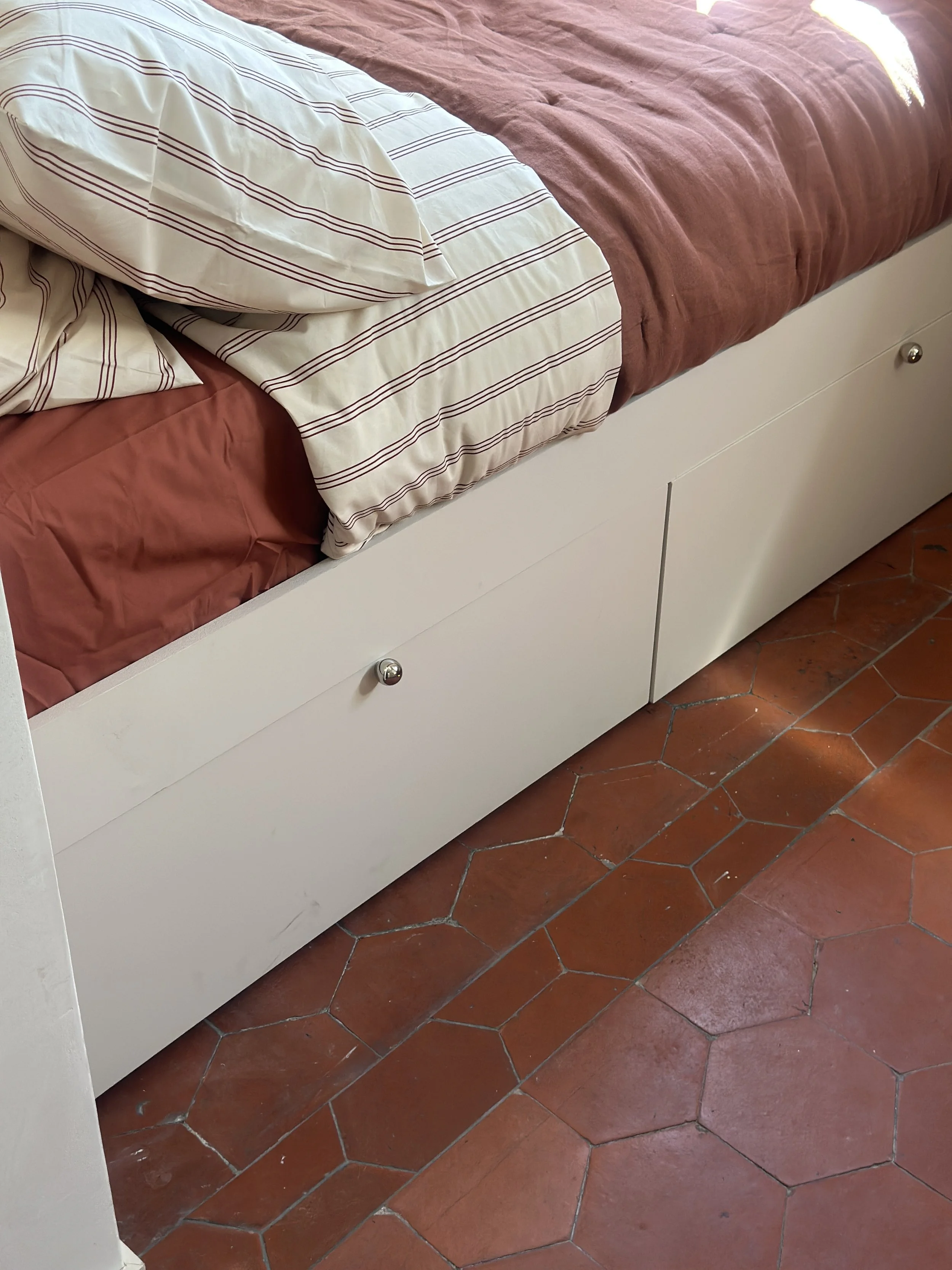Tomettes anciennes conservées et reposées au pied du lit sur mesure