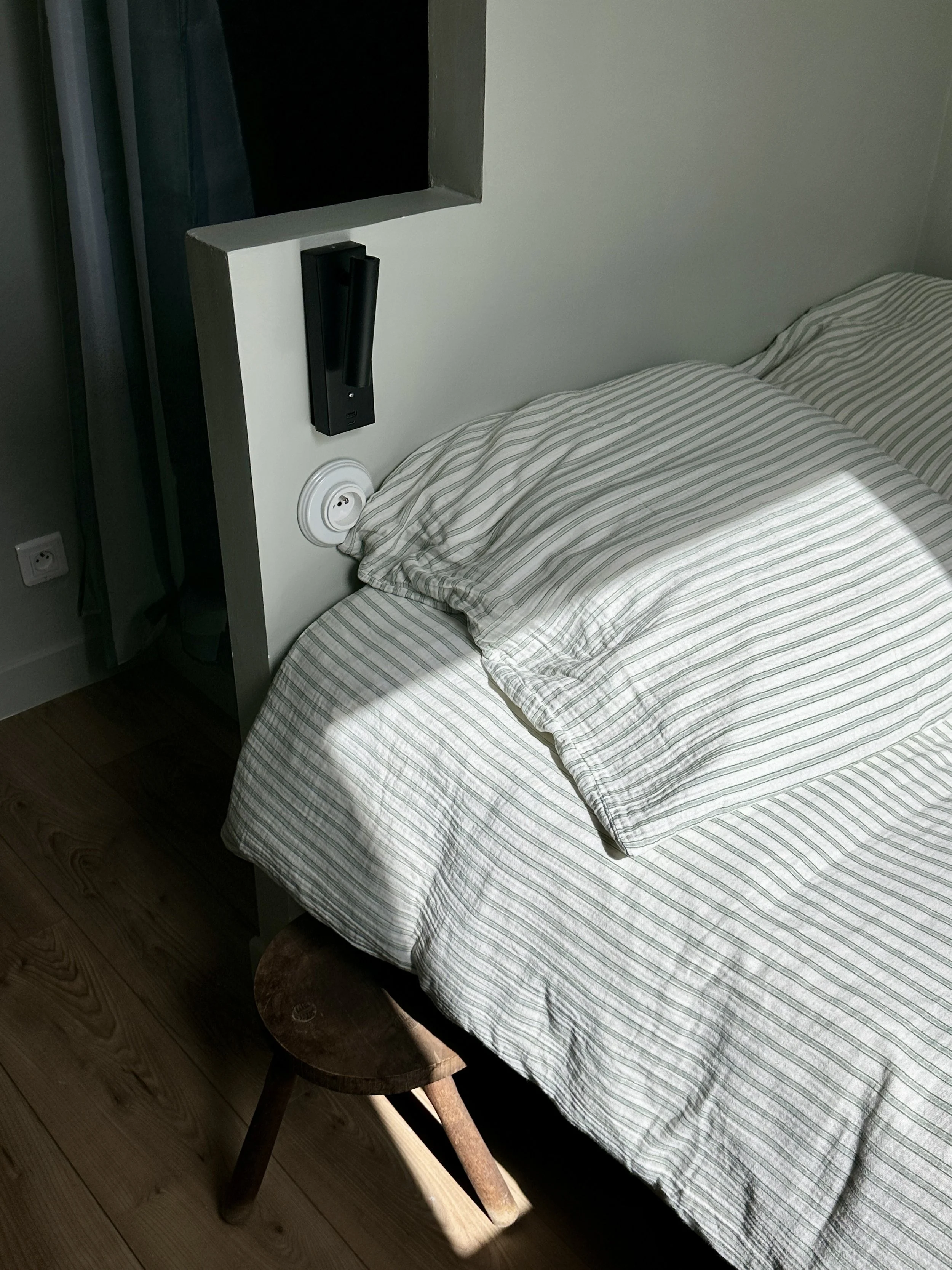 Bedroom detail with striped bedding and soft daylight.