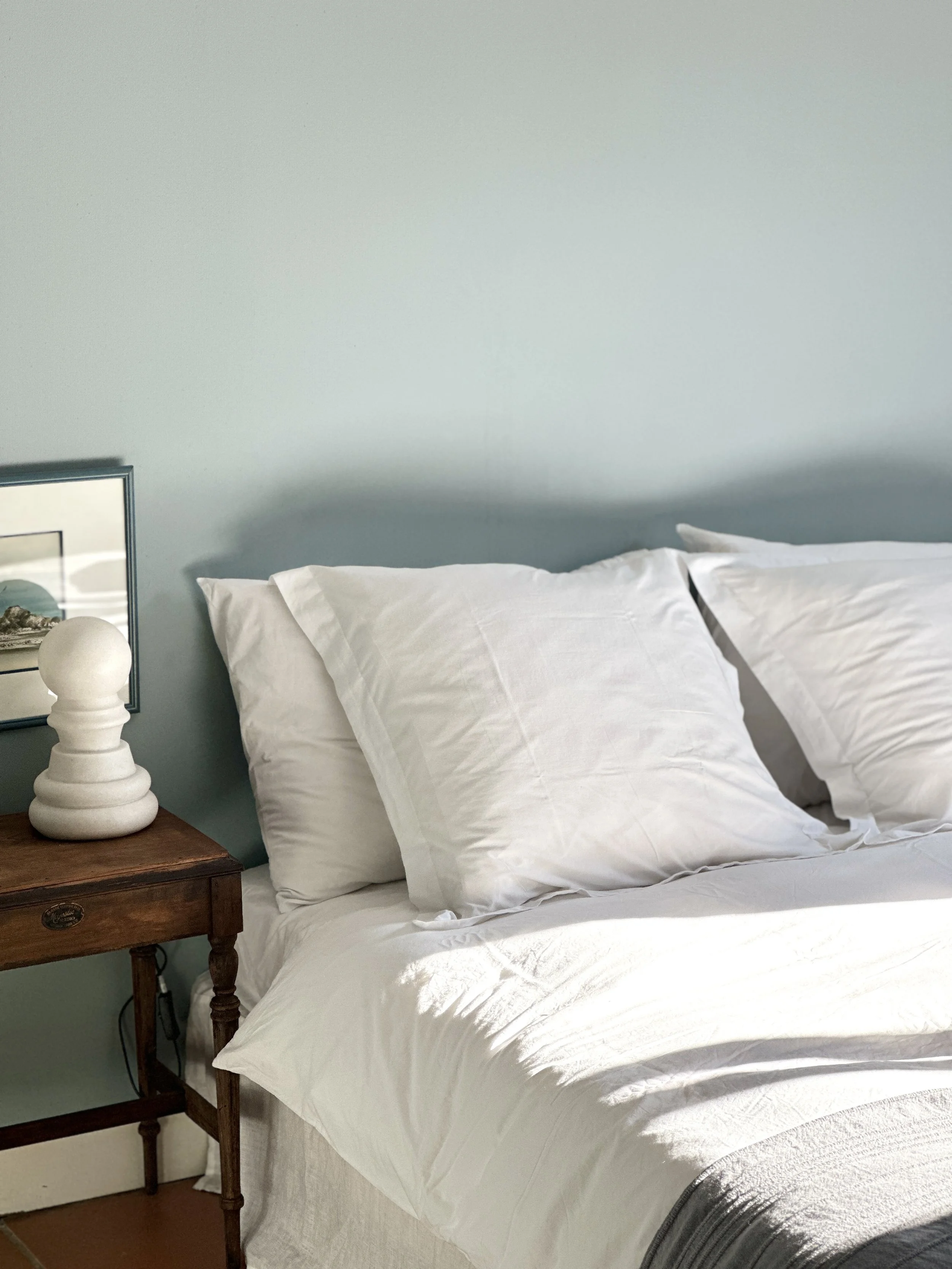 Chambre au linge blanc, table de chevet chinée et lampe en plâtre