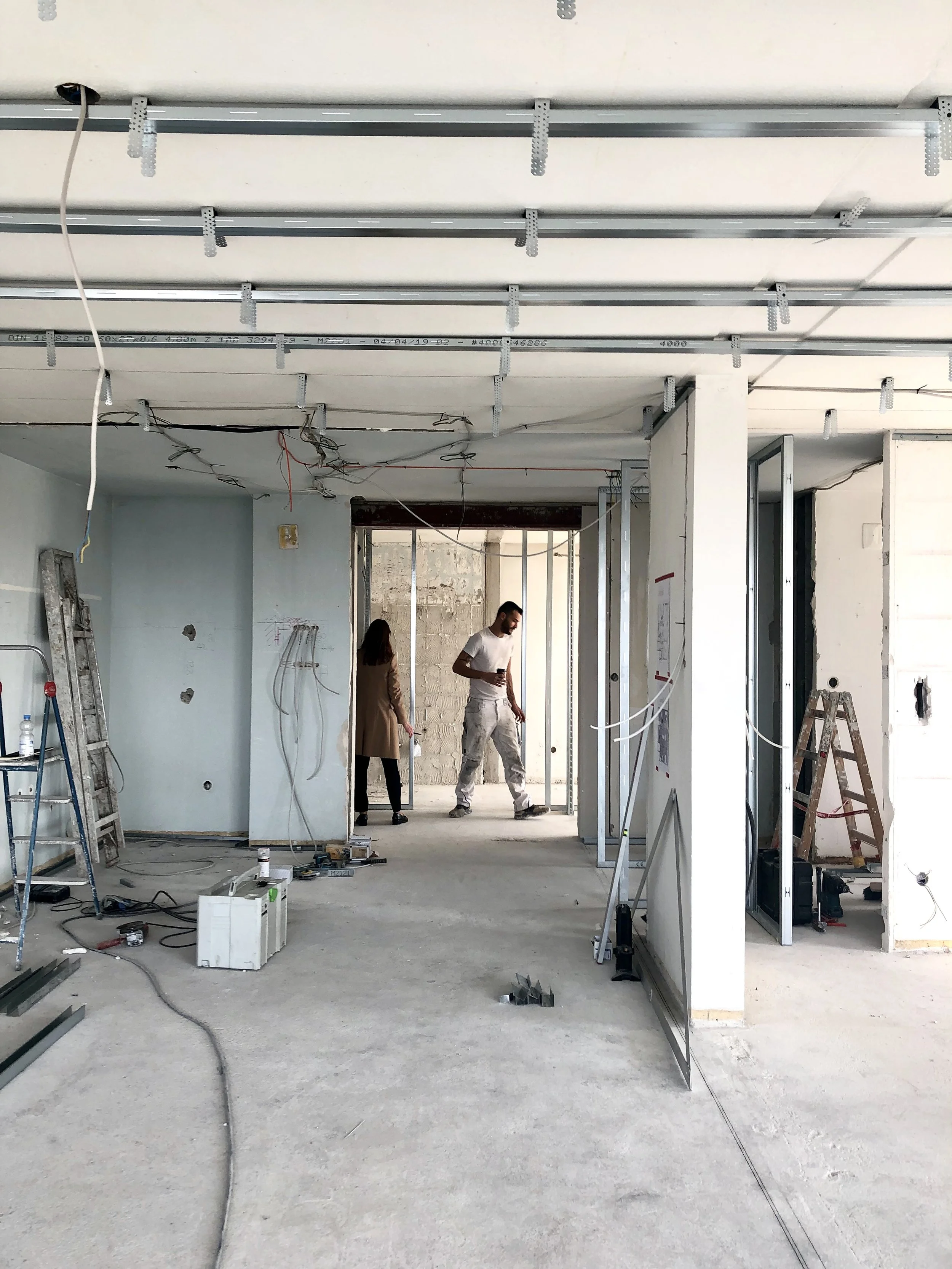 Chantier : plateau brut de l'appartement, réseaux apparents au plafond et cloisons en cours de montage