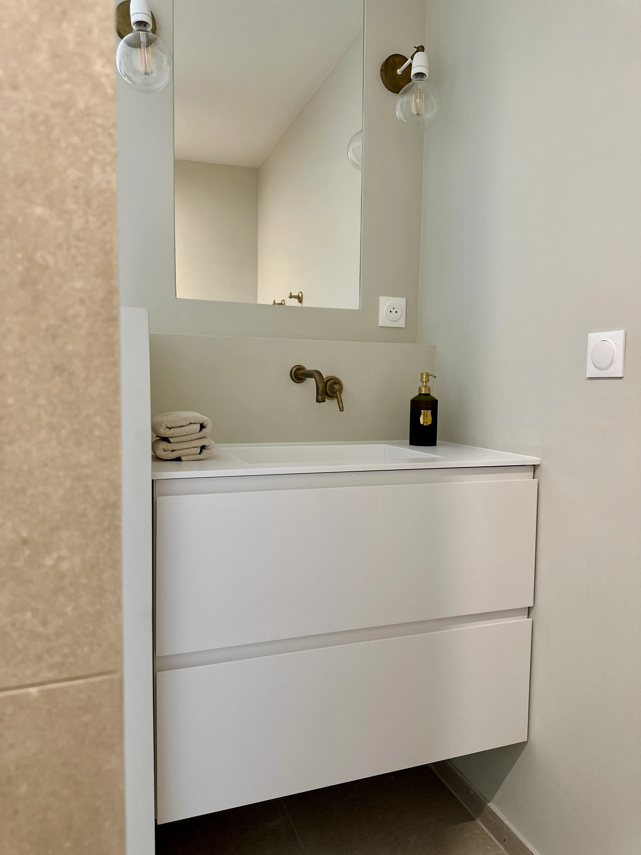 Meuble vasque suspendu dessiné sur mesure et réalisé par Riluxa, vasque intégrée, robinetterie en laiton brossé, miroir et appliques