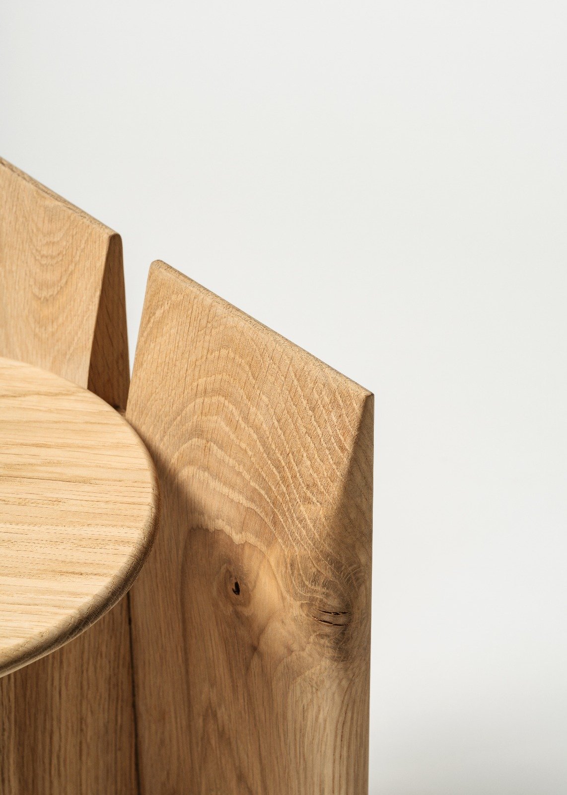 A modern wooden stand with a circular seat and two vertical back supports, set against a plain white background.