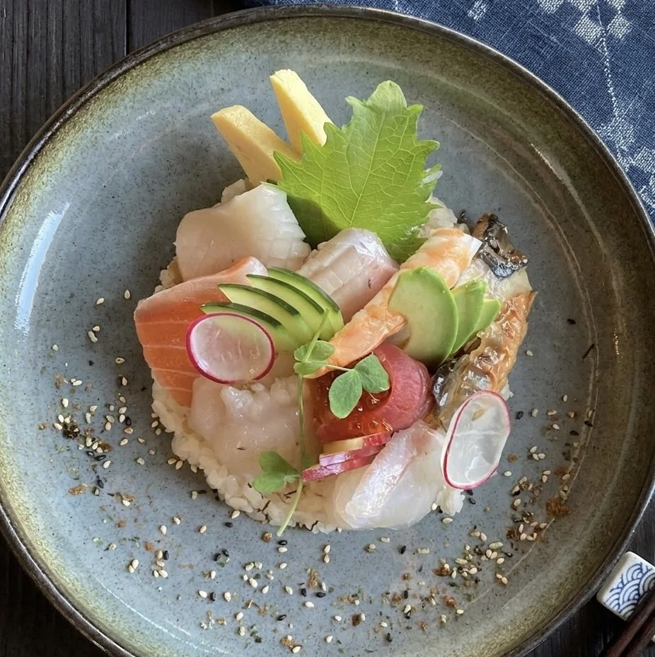 Chef Chirashi. Plate of assorted sashimi with sliced avocado, radish, cucumber, and garnishes, sprinkled with sesame seeds.