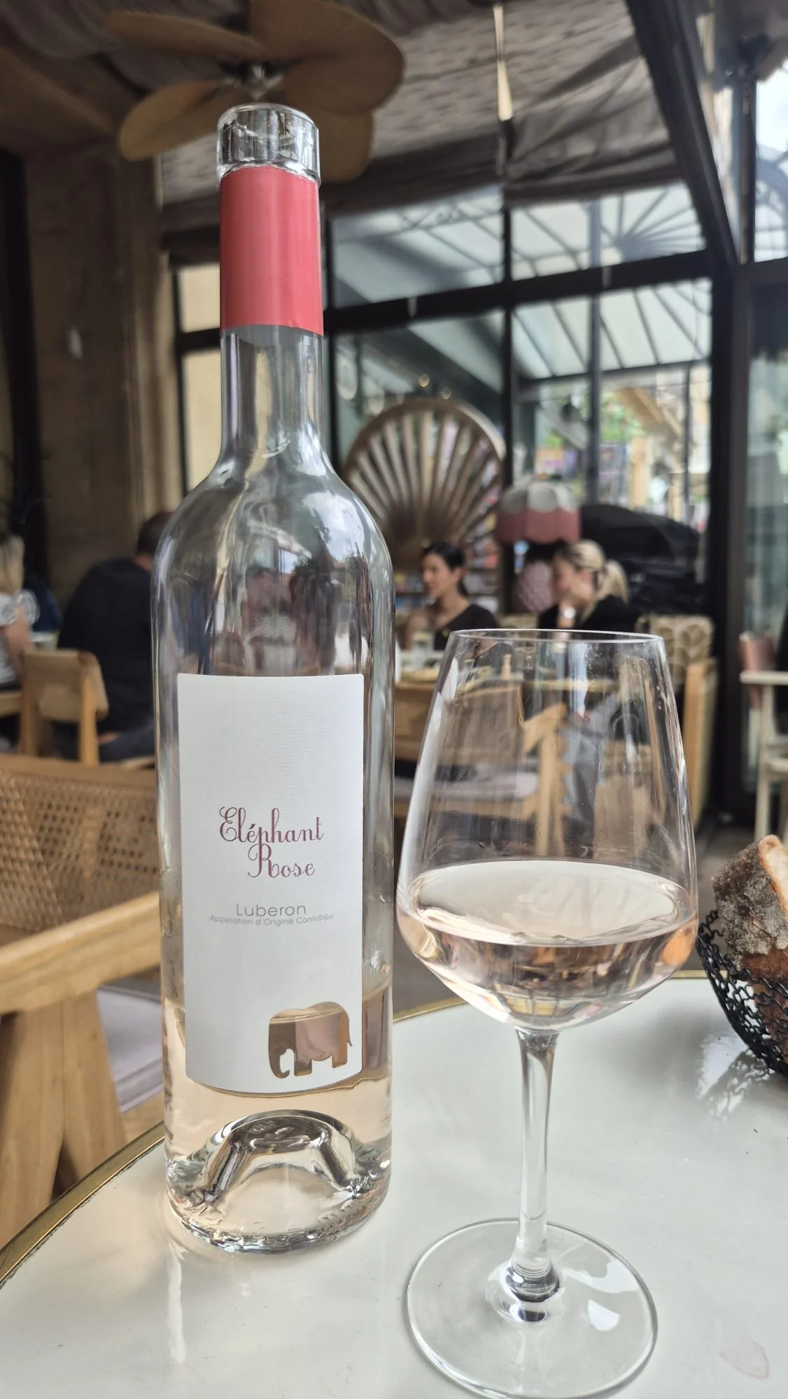 garrafa de vinho rosé aberta em cima da mesa com copo de vinho rosé ao lado direito