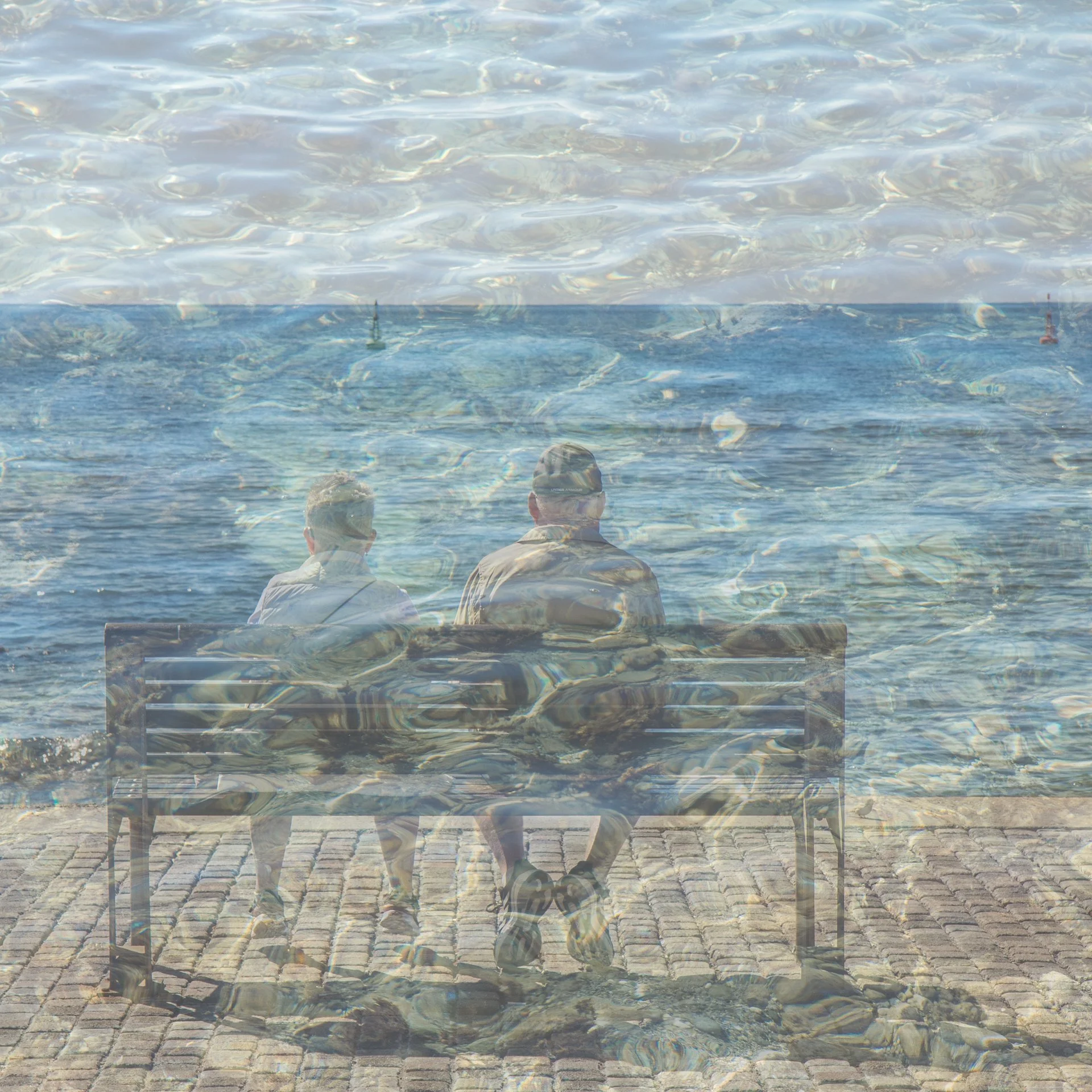 Two men sitting on a bench by the water, with their backs facing the camera. The image has a double exposure effect blending the scene with water ripples.