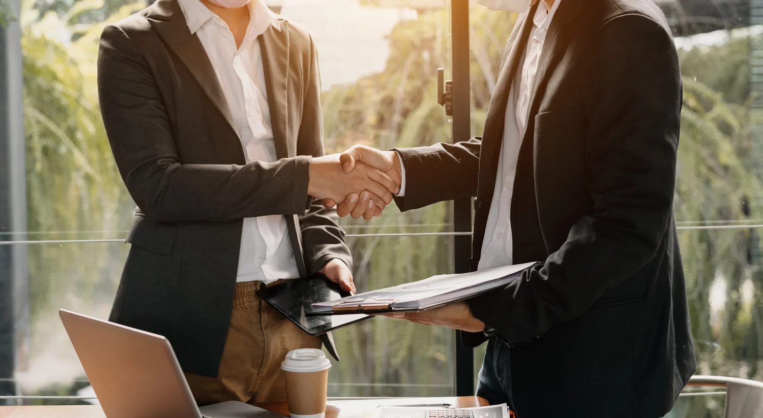 Two business professionals shaking hands in an office.