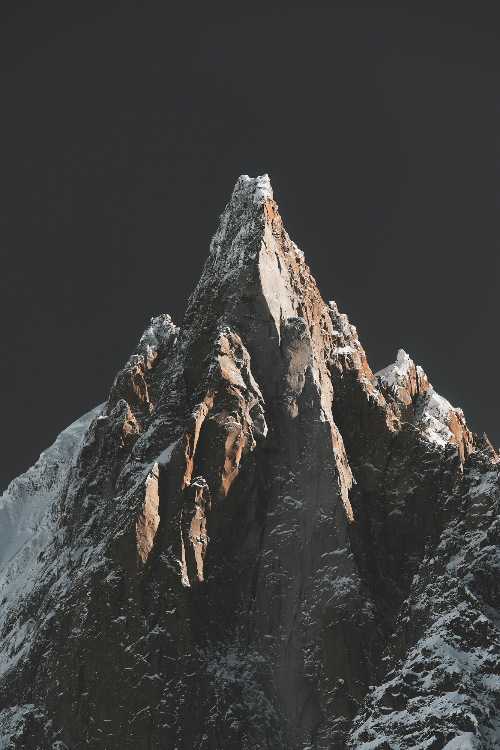 Snow-capped mountain peak against a dark sky.