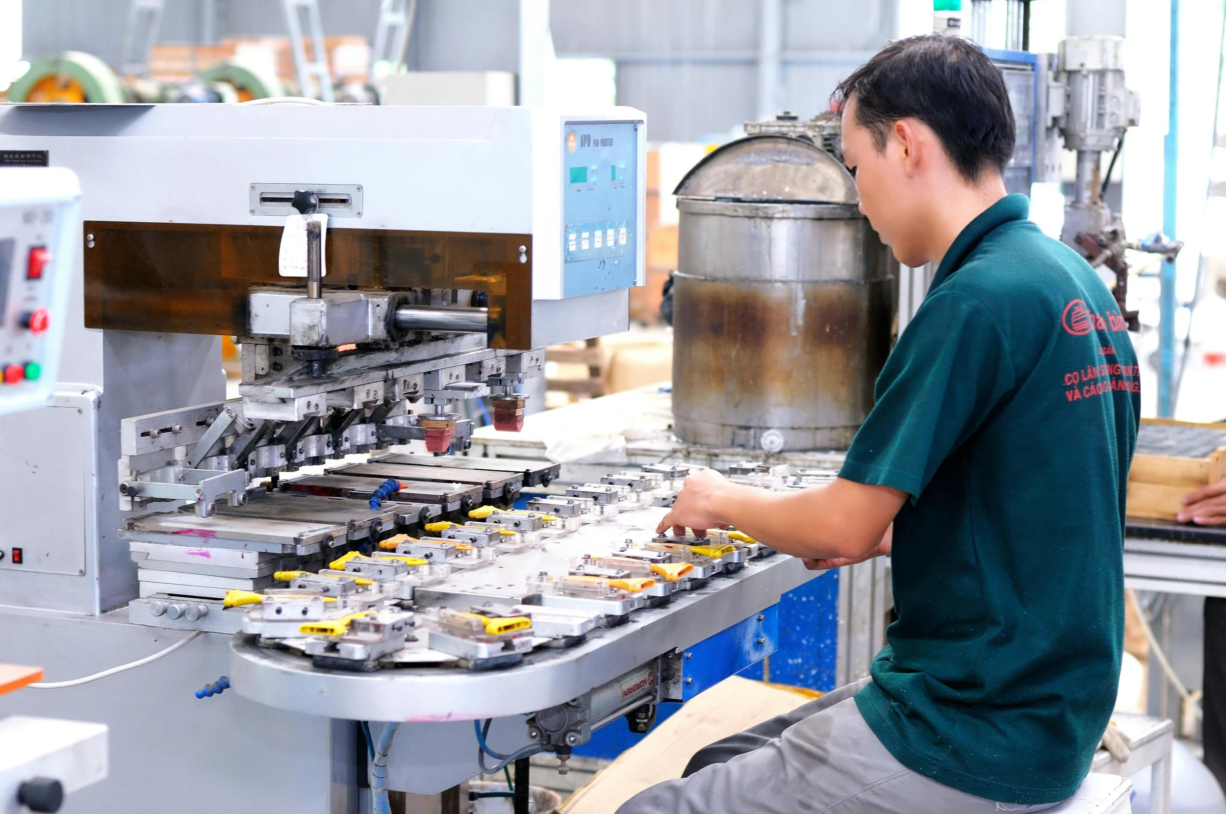 A person working with electronic components at a manufacturing or assembly station in a factory setting.