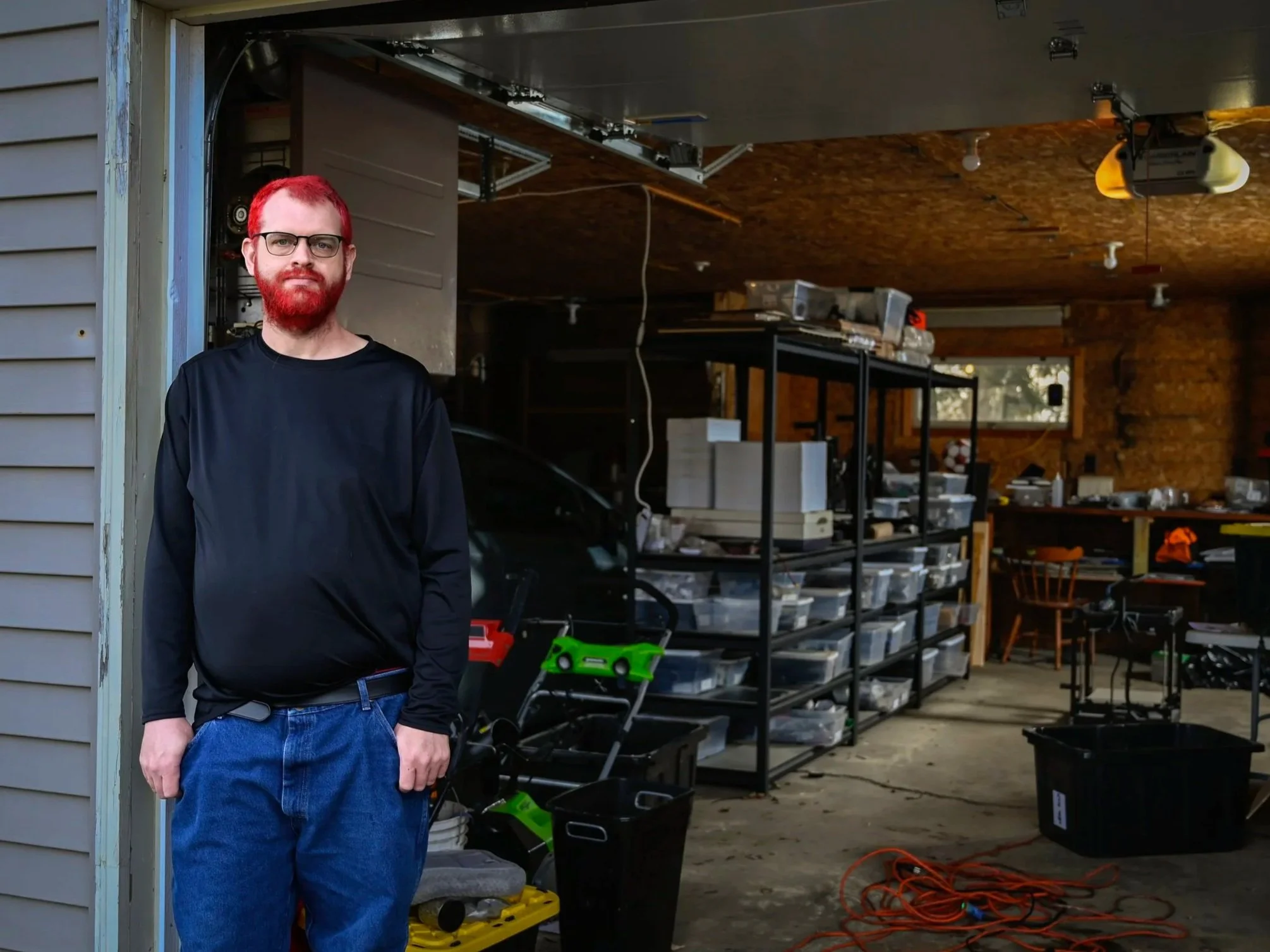 Zack Kummer, a student at UW-Oshkosh, stands in front of his garage, where he's organized his work supplies in Oshkosh, Wis., on March 10, 2025. Kummer is a mechanical engineer and said he was still bleeding from President Donald Trump's first term d