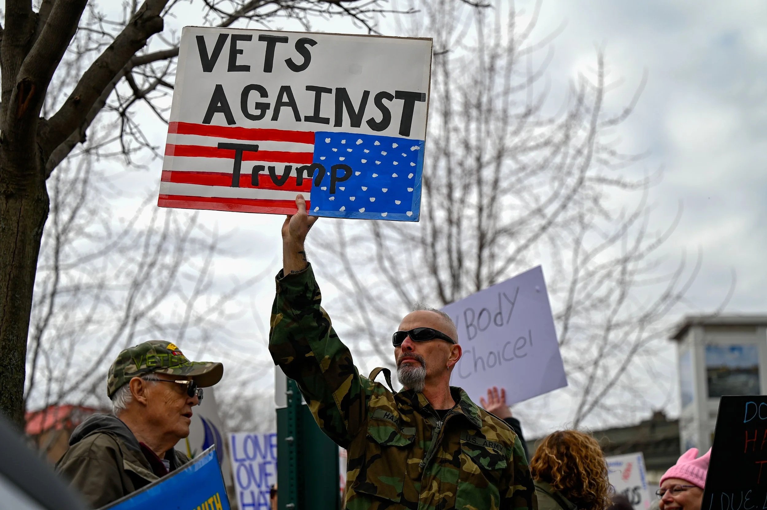 Veterans hold signs in protest at Houdini Plaza in Appleton, Wis., on April 5, 2025. The "Hands Off!" protest was originally started by Indivisible, an activist group that opposes President Donald Trump and supports progressive policies.