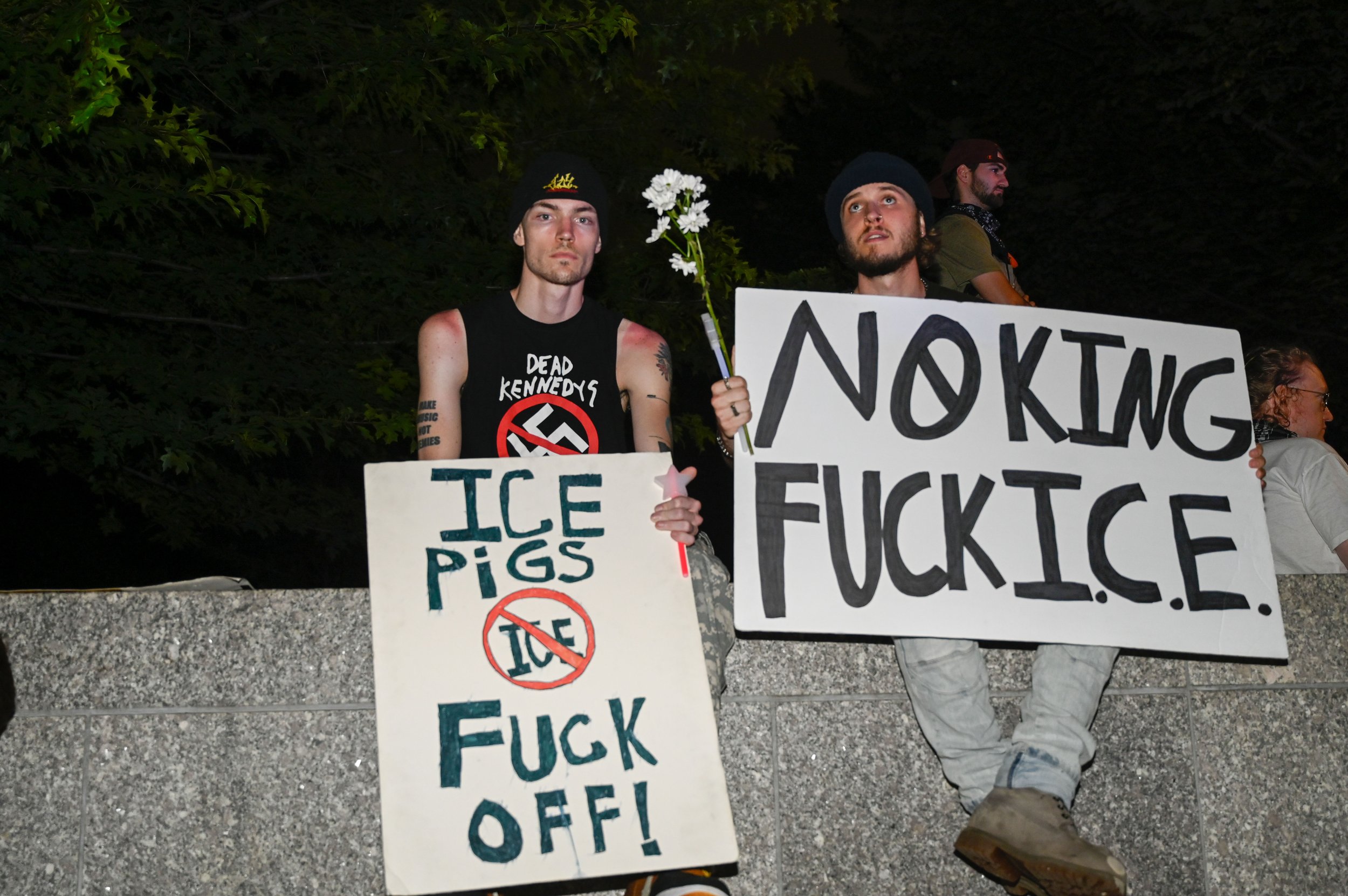 Two protesters sit on a ledge during a protest down the street from the Army's 250th birthday celebration in Washington, D.C., on June 14, 2025. There were reportedly 5 million people protesting in more than 2,000 planned protests around the nation.