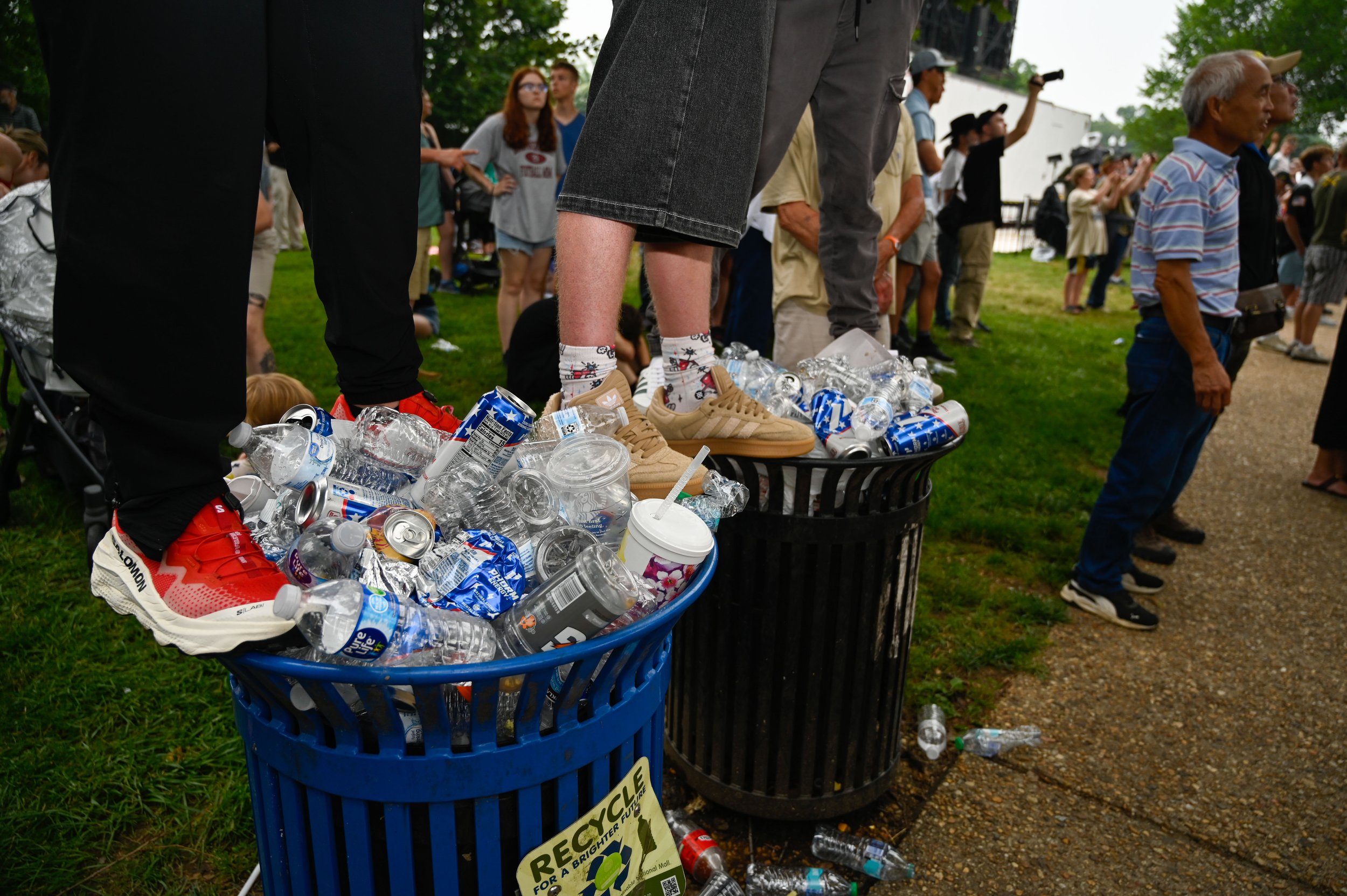 A group stands on overflowing waste bins to get a better view of the ensuing military parade in Washington, D.C., on June 14, 2025.