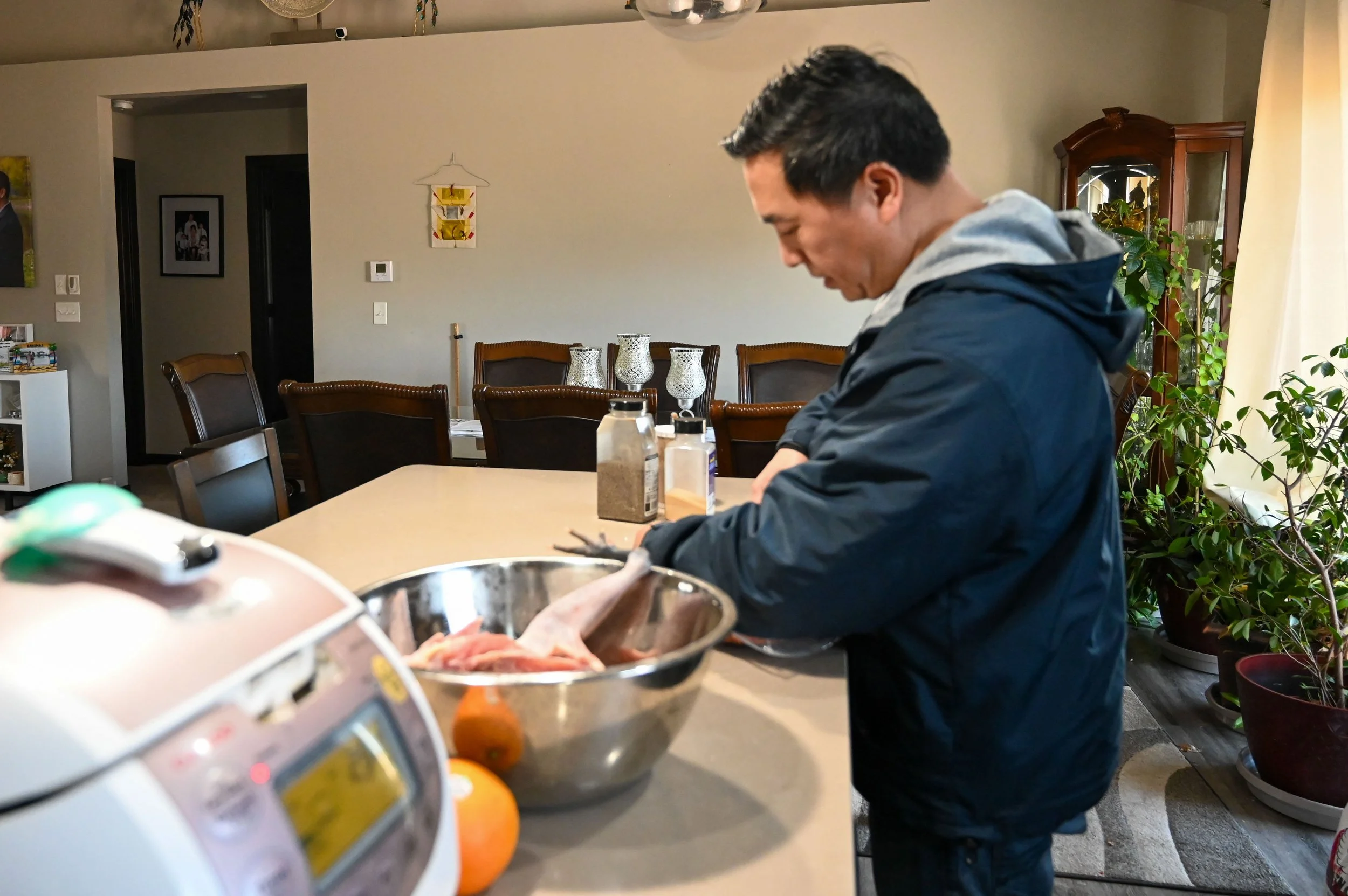 Sher Xiong prepares chicken for his children while his wife is at work in Appleton, Wis., Tuesday, March 10, 2026. Though Xiong believes in traditional gender roles and his wife was a stay-at-home mom for 15 years, she began working for Keurig 10 yea
