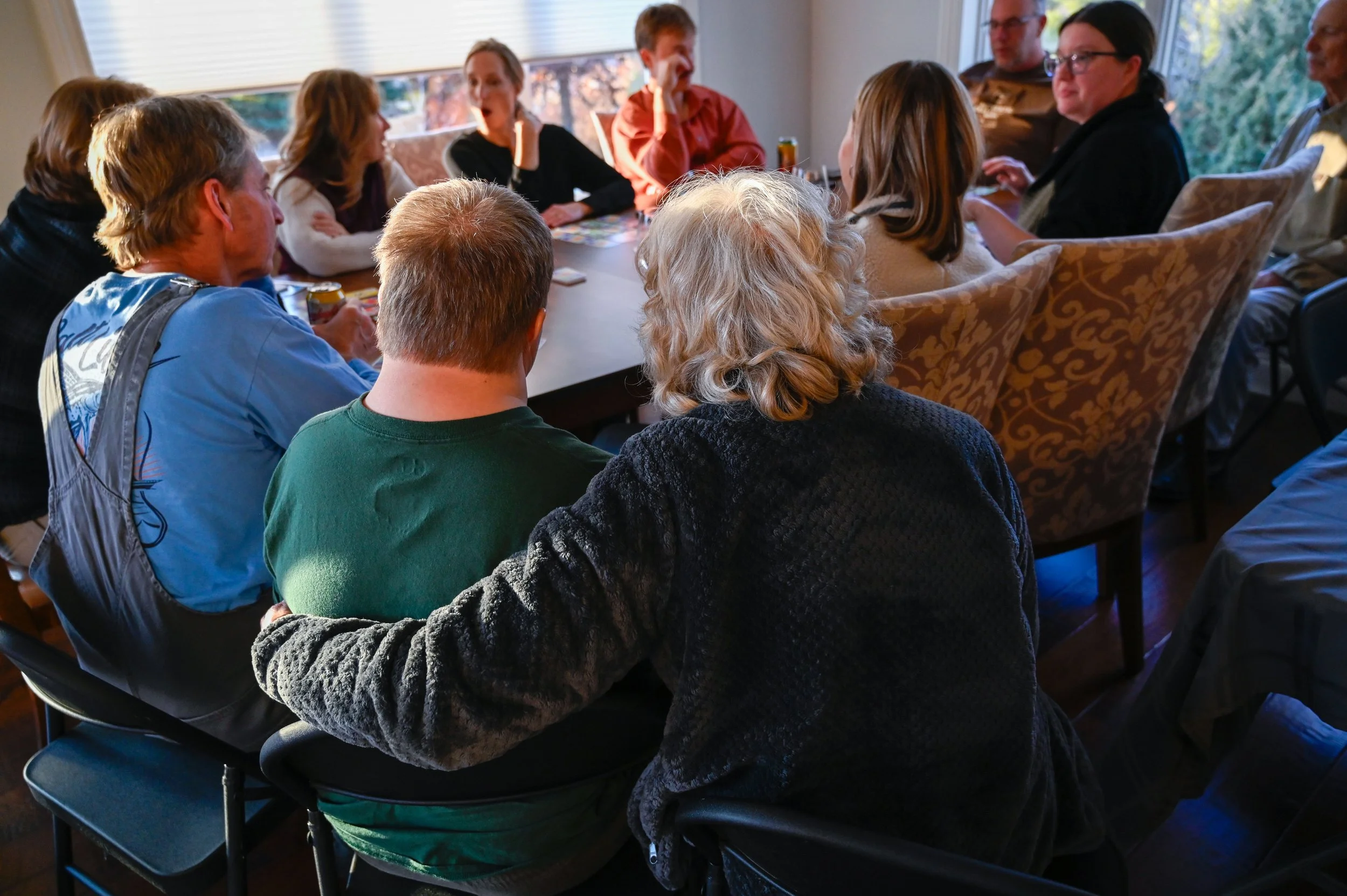 Janet puts her arm around Chad as they sit to watch the rest of the family play a card game. 