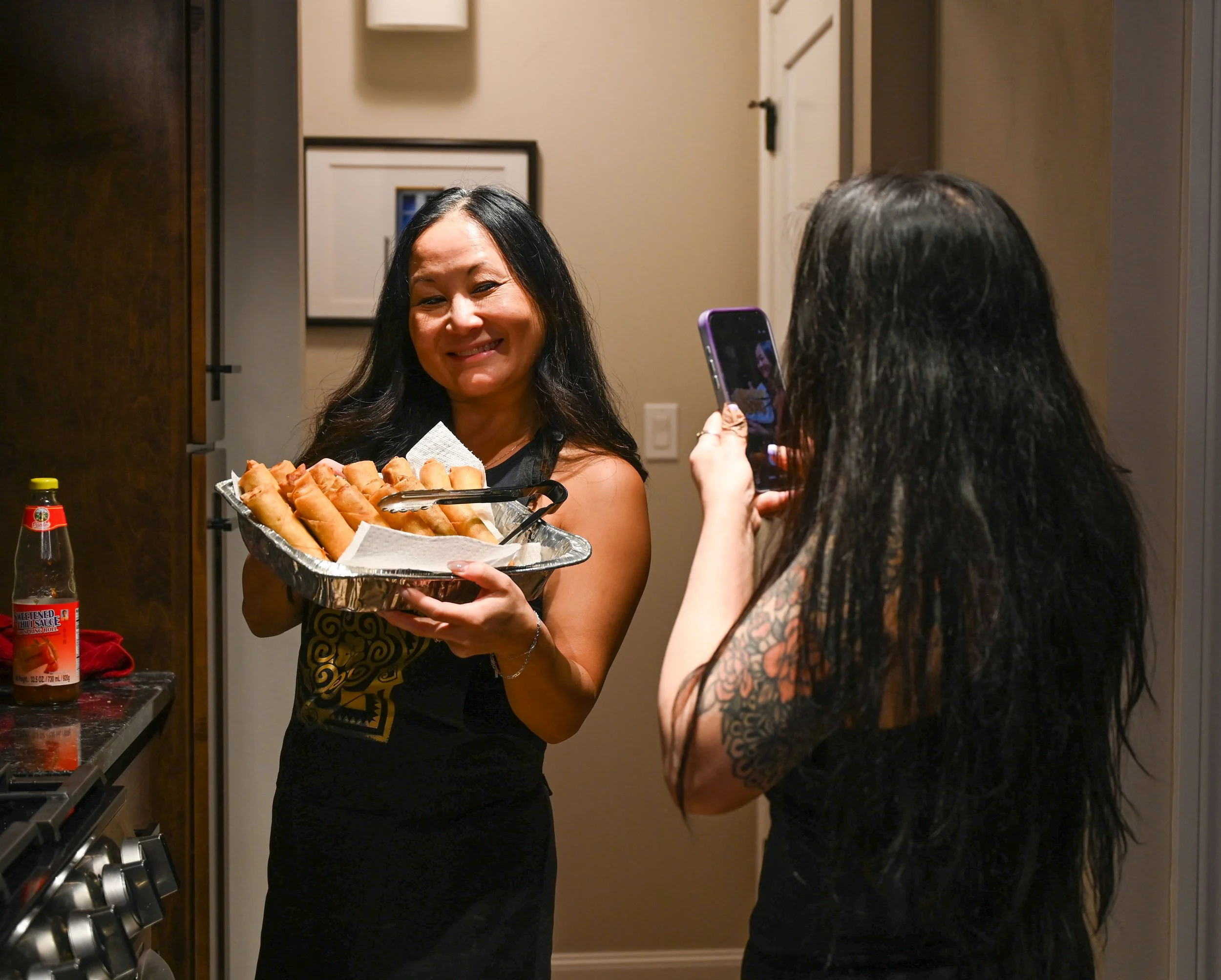 Yami Sweeny poses with her freshly fried egg rolls as her aunt Dolly takes a photo for Facebook in Shawano, Wis., Sunday, March 29, 2026. The pair got together that night to cook Hmong Soup. Sweeny said in Hmong culture, it's common for women to cook