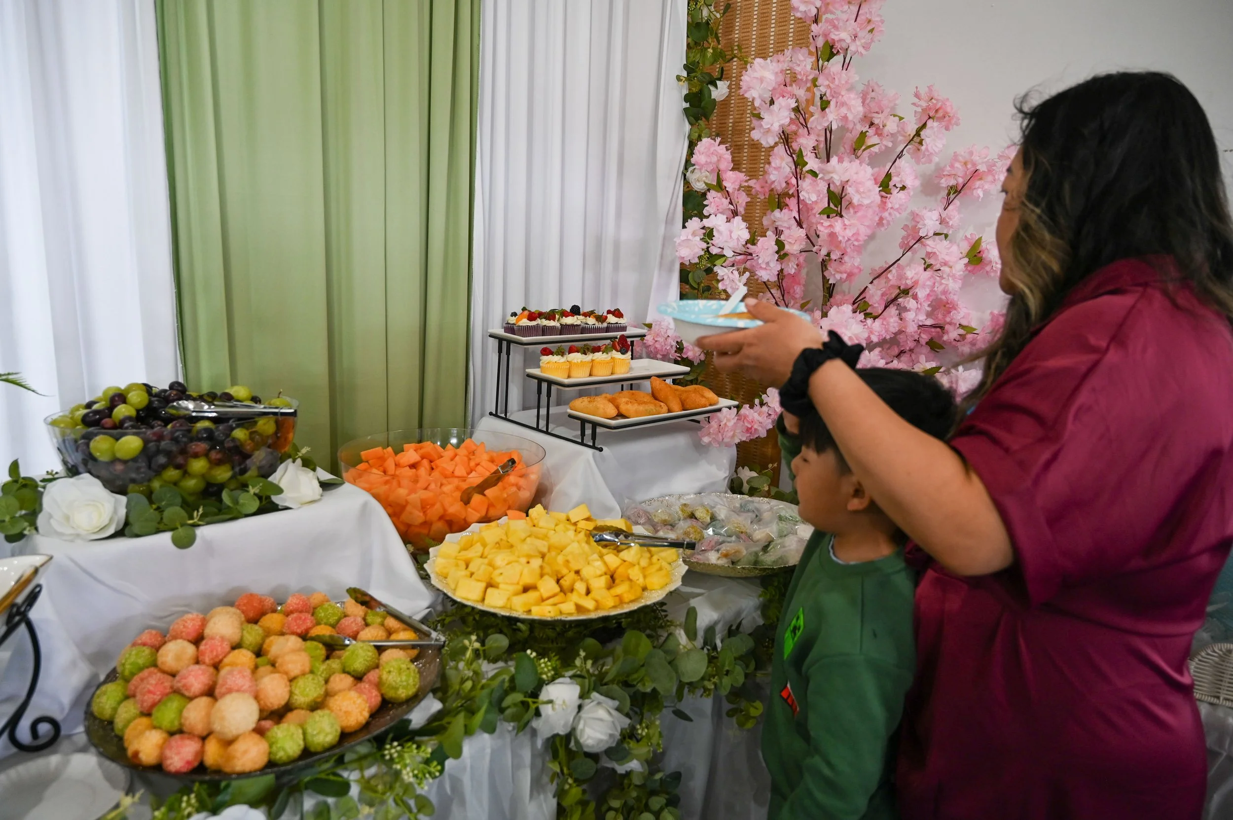 A mom brings her son with her to make him a plate of food at a Hmong name change ceremony in La Crosse, Wis., Saturday, April 18, 2026. In Hmong culture, women cook, clean, and often make plates for children. 
