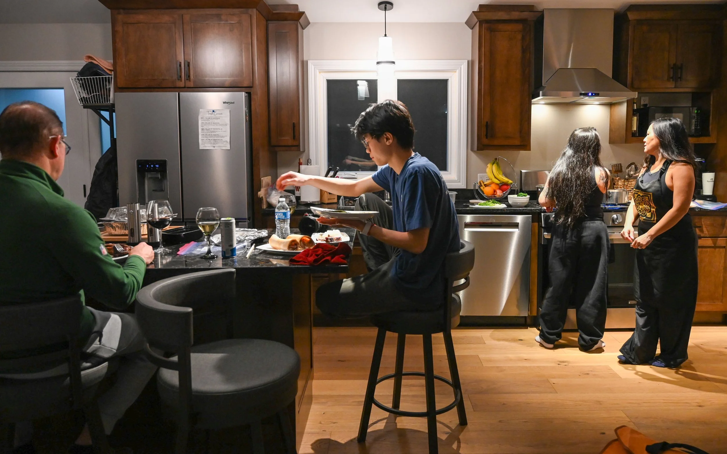 Kenneth Lee and Robert Sweeny sit down to eat appetizers and Yami Sweeny and her aunt Dolly work on cooking their Hmong Soup in Shawano, Wis., Sunday, March 29, 2026. Though Yami is detached from Hmong culture, she said she still believes in its trad