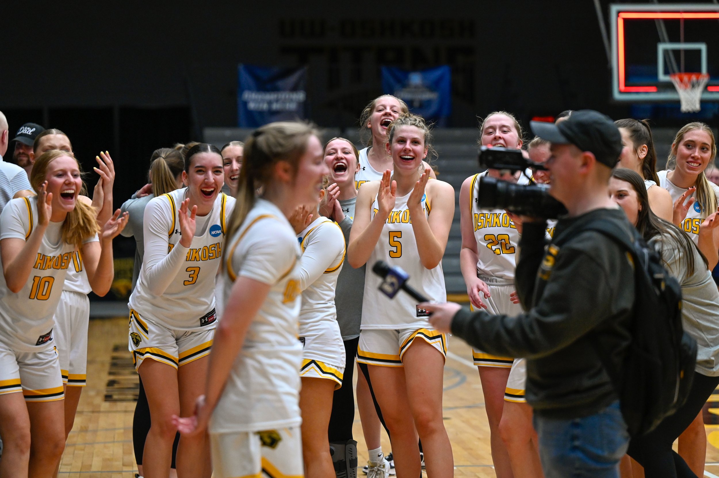 Players from the UW-Oshkosh women's basketball team laugh and cheer on their teammate, Sammi Beyer, as she is interviewed by WFRV Local 5 news. Beyer later spoke at a press conference with her teammate, Alex Rondorf. (Photo by Advance-Titan Photo Edi