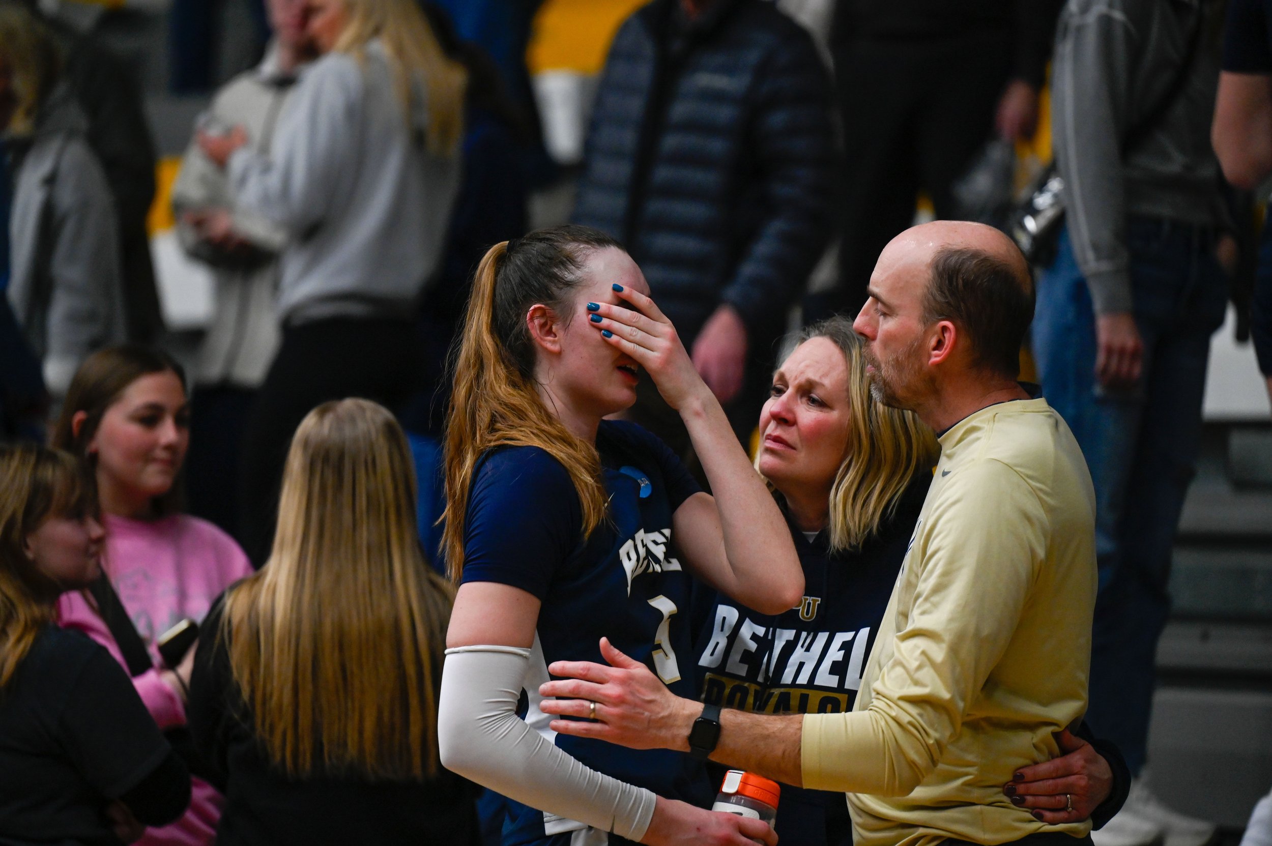 Elly Schmitz, a guard and forward for Bethel University's women's basketball team, is comforted by her parents, Elisa and Joe Schmitz, after a loss to UW-Oshkosh at Kolf Sports Center on March 8, 2025. The loss meant the end for Bethel's women's bask