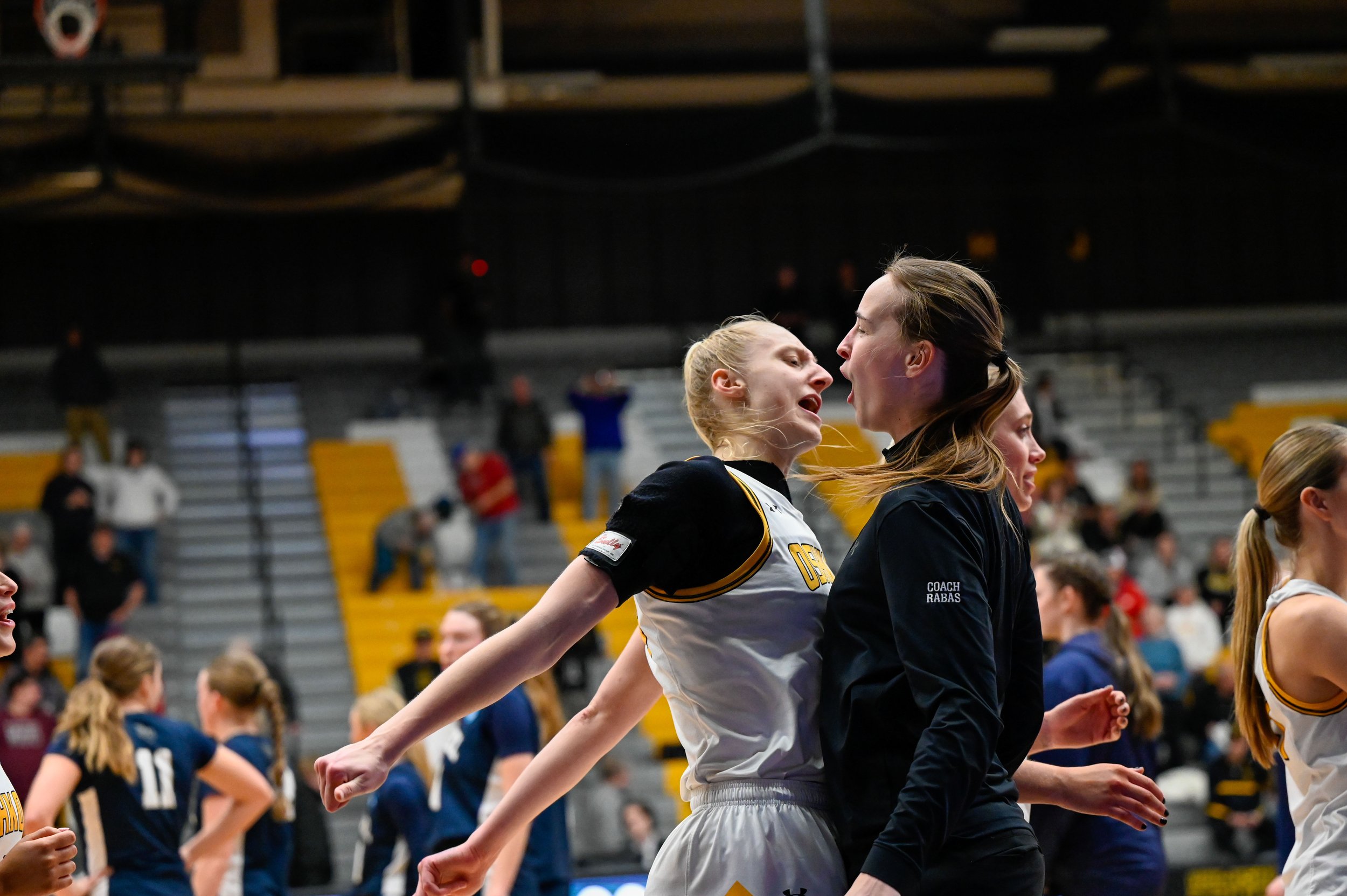 Kayce Vaile, a fifth-year forward for the UW-Oshkosh women's basketball team, chest bumps assistant coach Jessie Rabas at Kolf Sports Center in Oshkosh, Wisconsin, on March 8, 2025. Vaile and Rabas had just finished the post-game handshake line and w