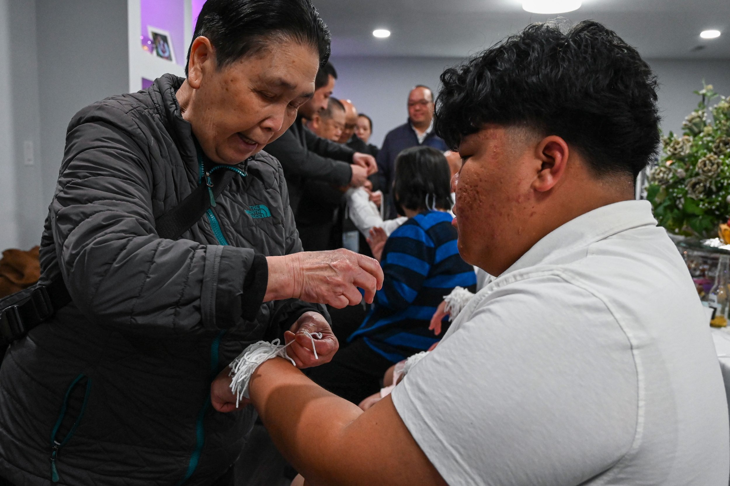 A boy receives a blessing during the hand-tying ceremony at a Hmong elder name change ceremony in La Crosse, Wis., Saturday, April 18, 2026. The white strings symbolize blessings and good health.