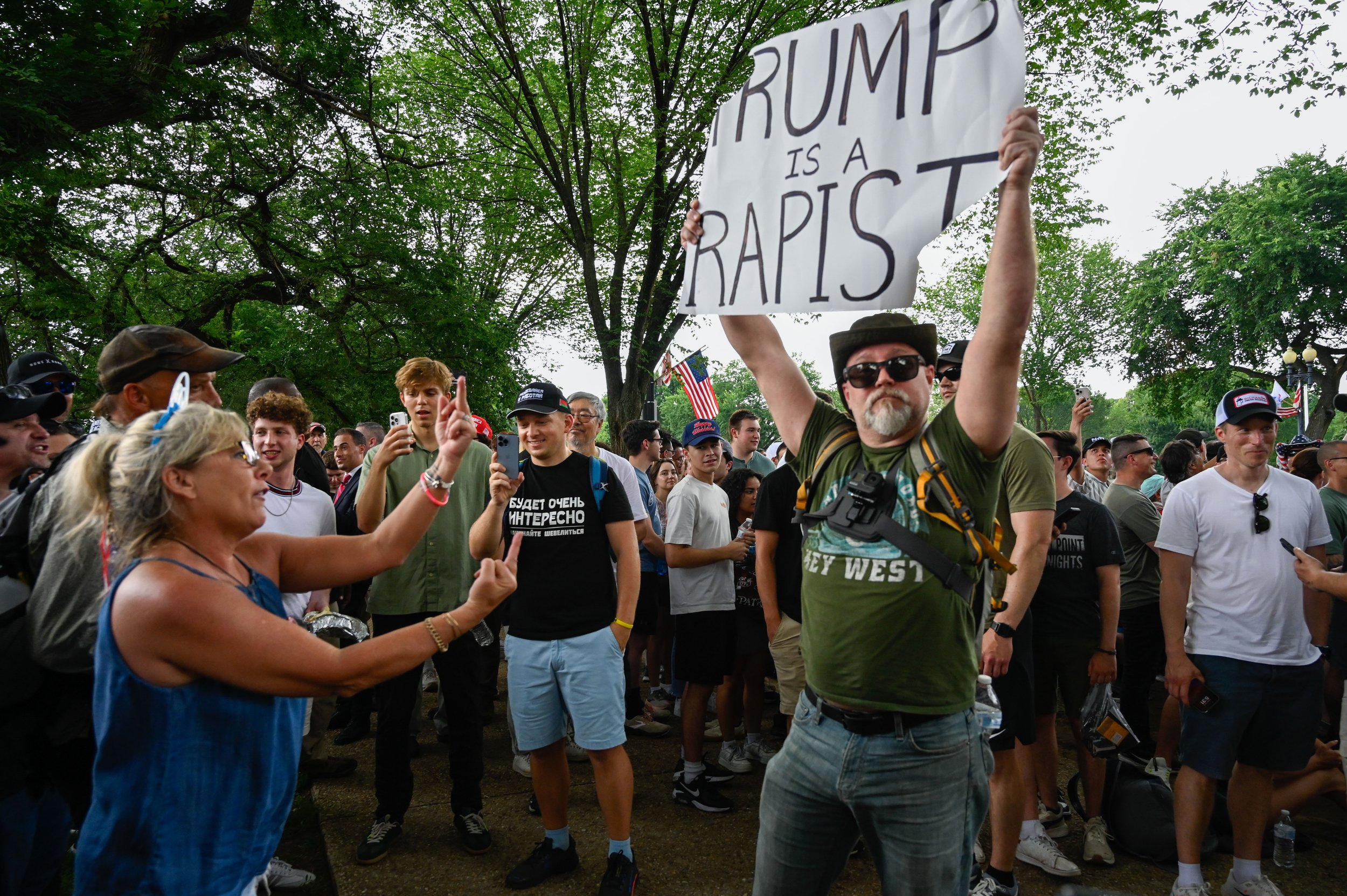 A woman gestures at a protester with middle fingers during the Army's 250th birthday celebration in Washington, D.C., on June 14, 2025. The woman argued with the man for several minutes before another man came by and ripped the sign from his hands.