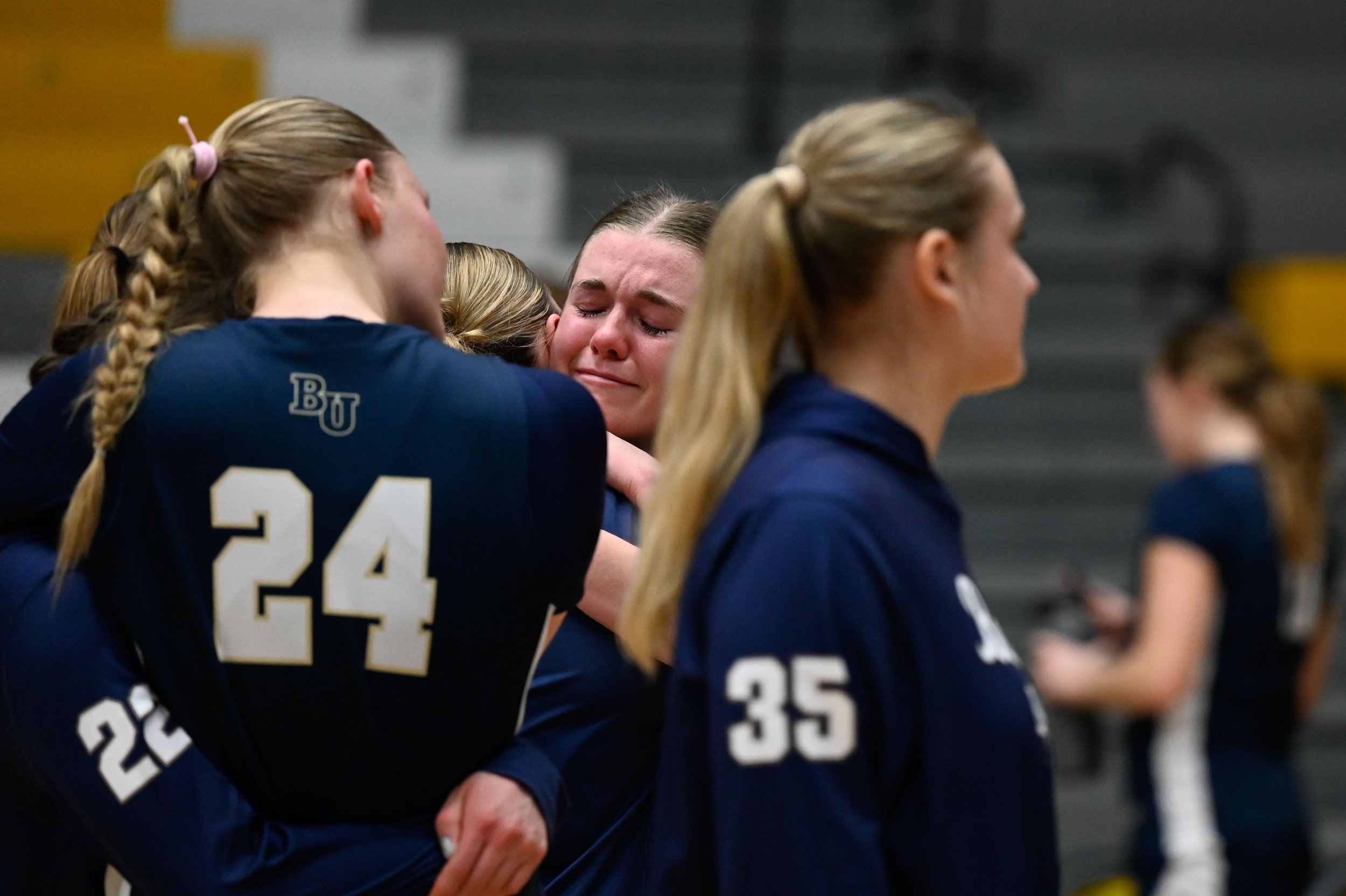 Rosalie Penke, a junior basketball player for Bethel University, cries while hugging her teammates after a loss to UW-Oshkosh at Kolf Sports Center in Oshkosh, Wisconsin on March 8, 2025. The loss meant the end for Bethel's women's basketball team, a