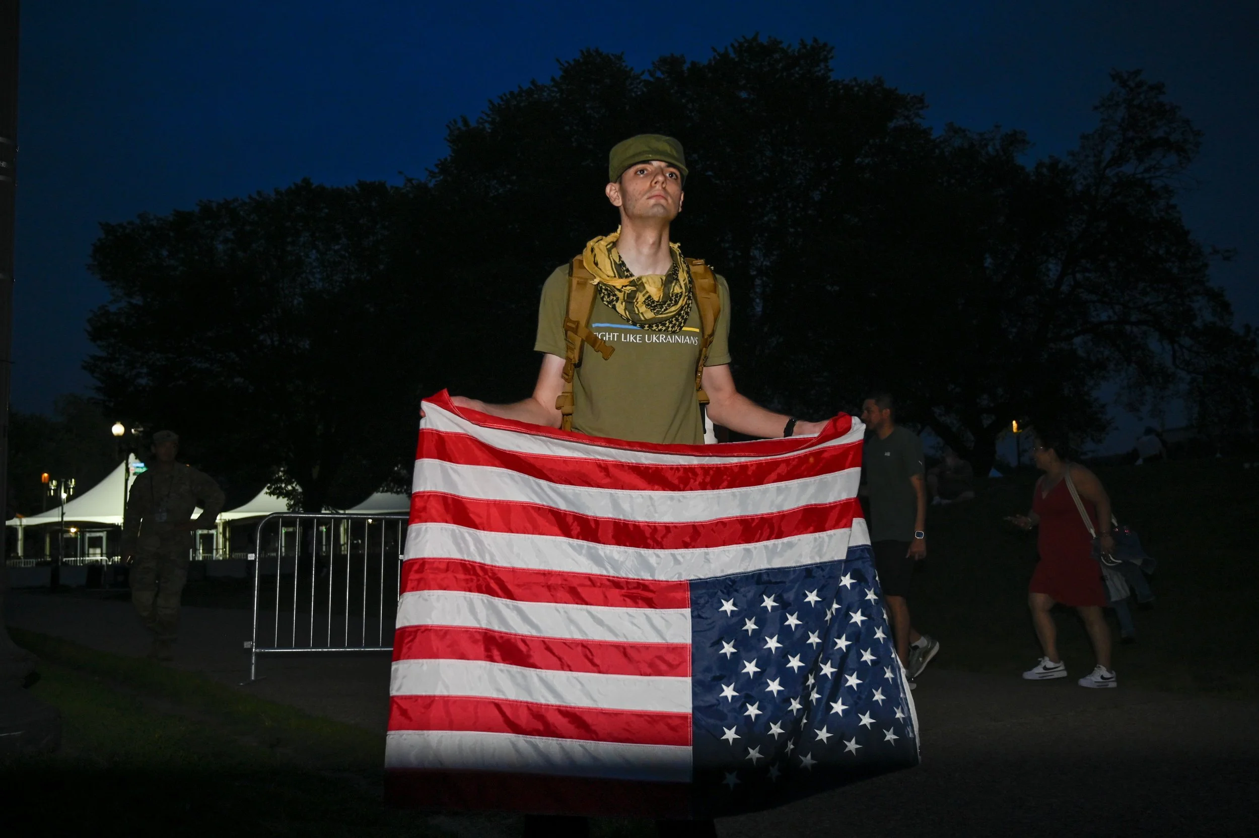Elliot Latzsch, a Marine veteran, holds an American flag upside near the exit of the Army's 250th birthday celebration in Washington, D.C., on June 14, 2025. Latzsch said he was holding it that way to signal distress in America. 