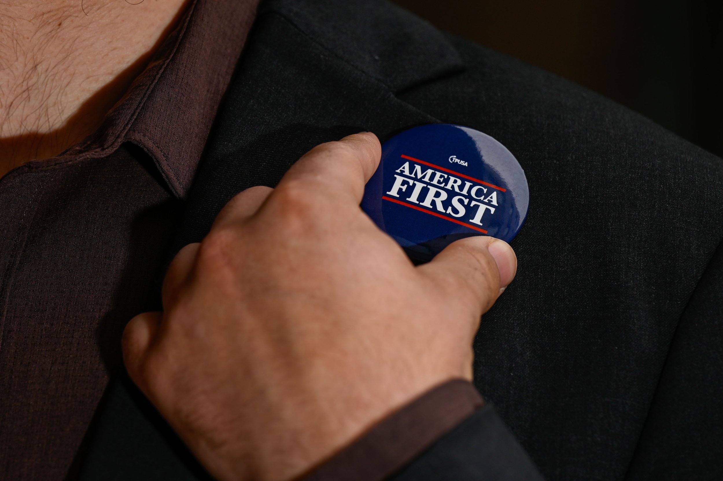 Marco Marchiando, a sophomore political science and history double major at UW-Oshkosh, holds a pin signaling right-leaning viewpoints, in Oshkosh, Wisconsin, on April 9, 2025. Marchiando said that while he sympathizes with people who may feel the ne