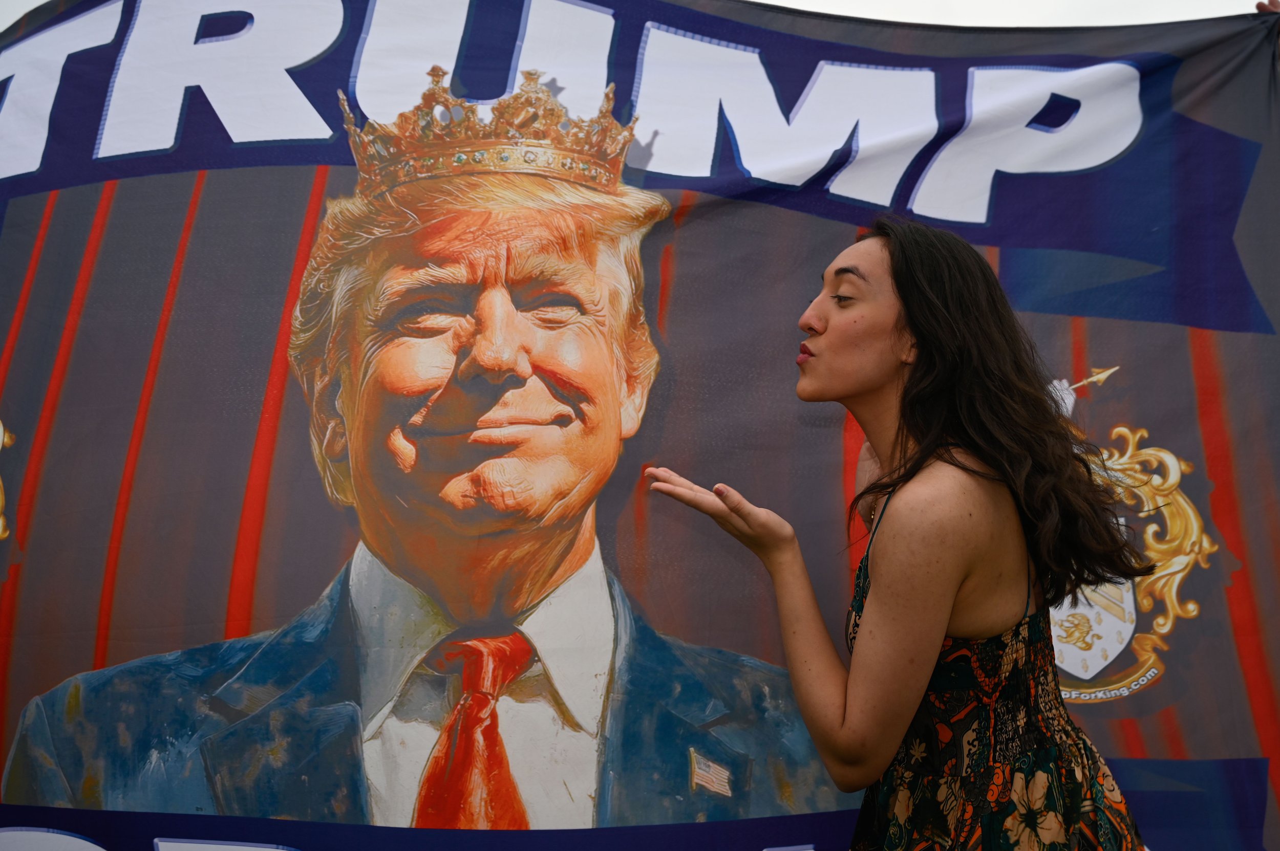 A woman pretends to blow a kiss at an image of President Donald Trump on a flag that says "Donald Trump for King" during the Army's 250th birthday celebration in Washington, D.C., on June 14, 2025.