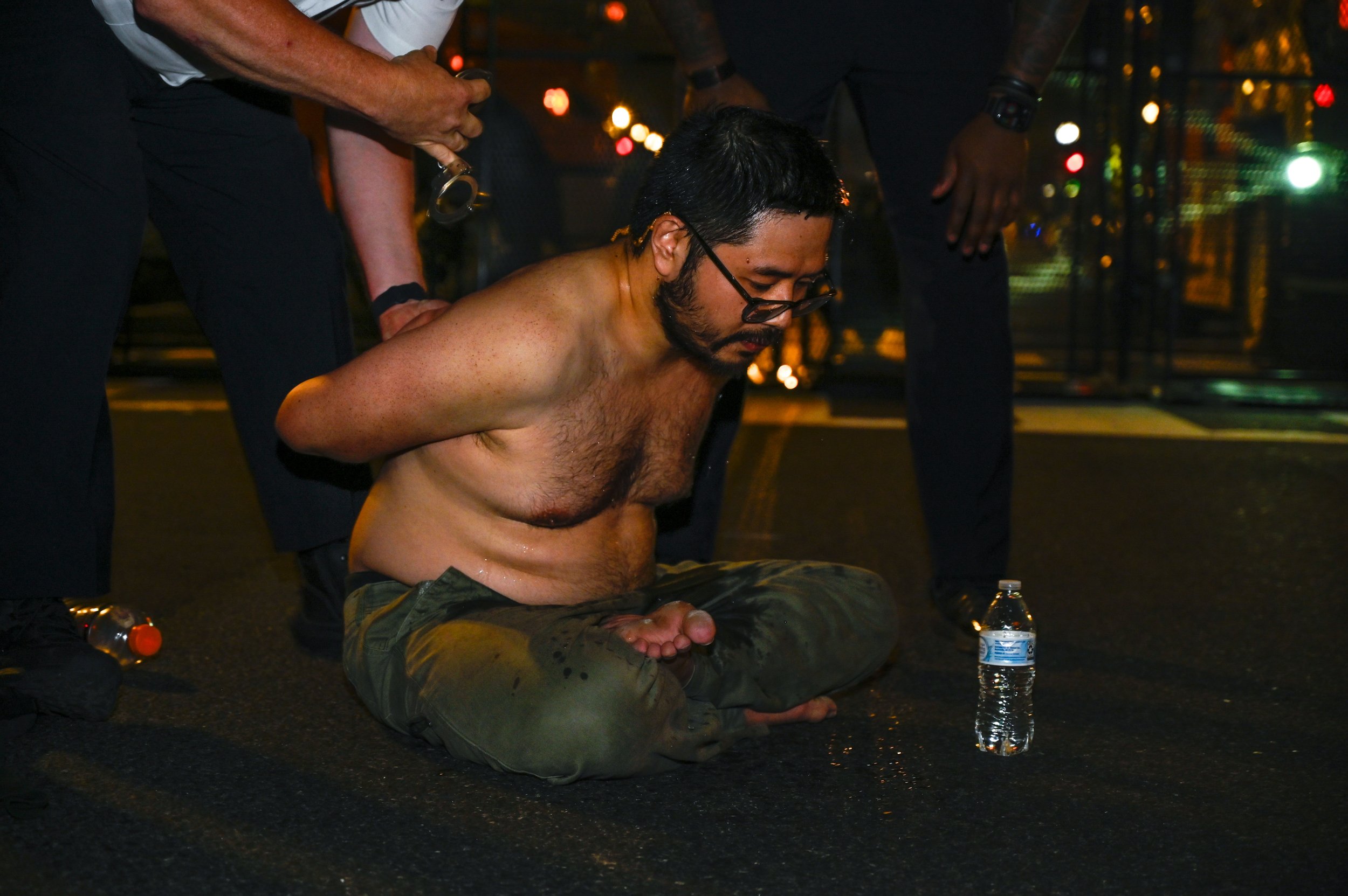 Police handcuff a man who sat in the street near protesters of the Army's 250th birthday celebration in Washington D.C., on June 14, 2025. The man appeared to have his belongings laid out in front of him and was having a conversation before tension b