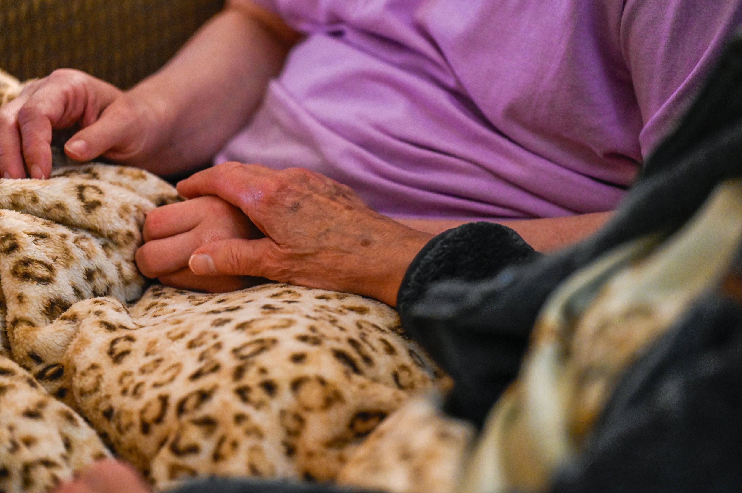 Janet places her hand on Chad’s as they watch television. 
