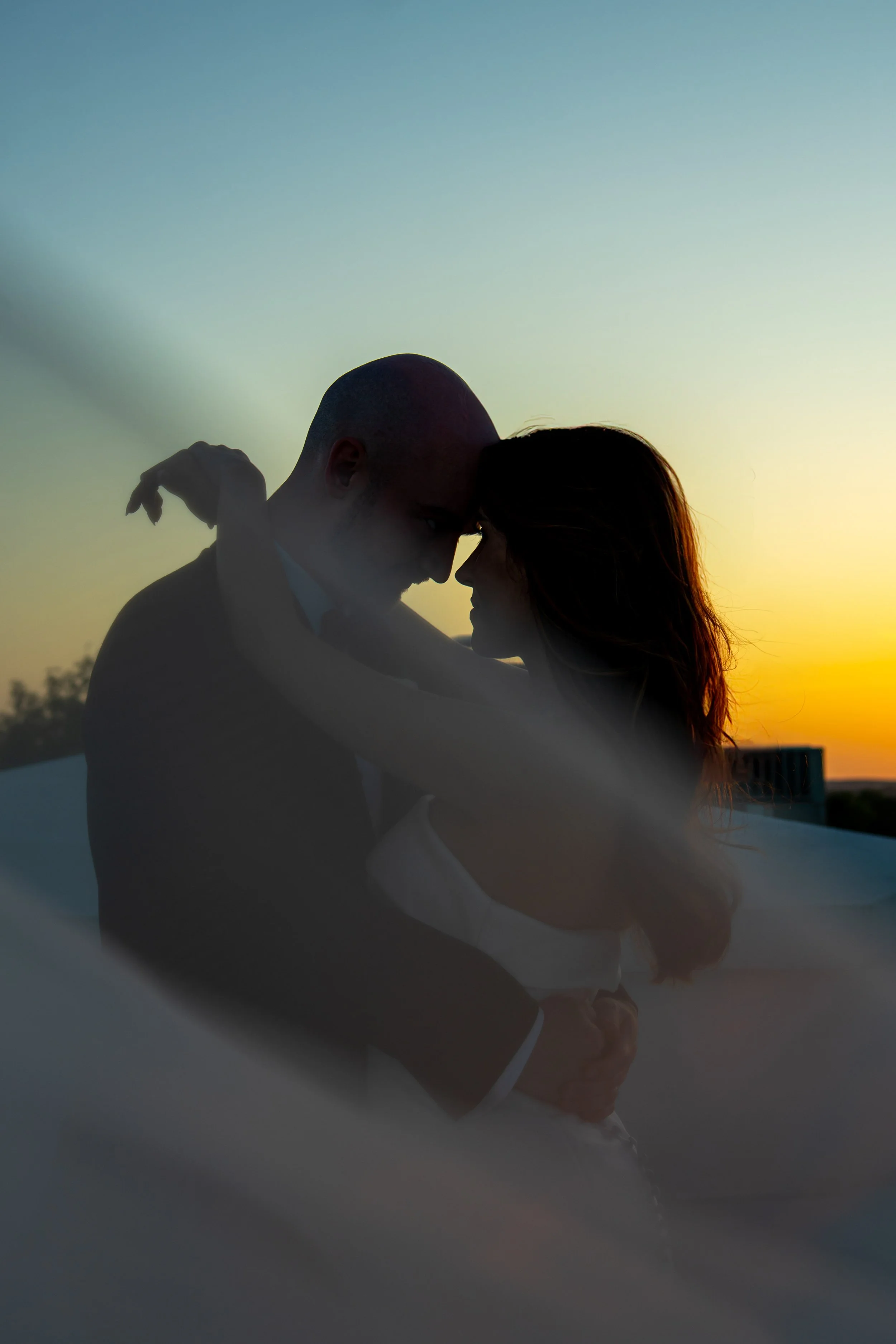 Silhouetted couple embracing at sunset with a colorful sky in the background. Taken by a Las Vegas Photographer Videographer