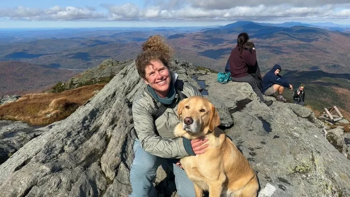 Rachel on top of a mountain with her dog.
