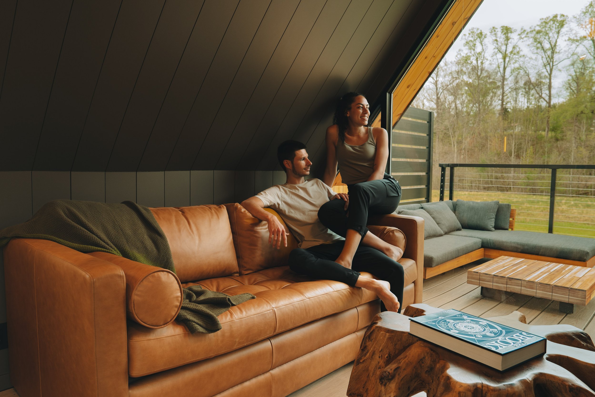 A woman wearing a black, shiny, sequined dress holding BSB-branded body oils and accessories, with gold jewelry and a Christmas-themed bow, in a festive setting.