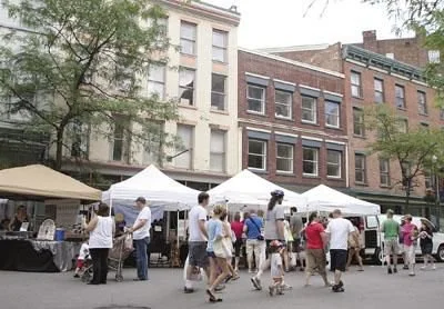 Color photo as published on troyrecord.com: shoppers among the vendor tents on River Street at the market’s first Saturday at its new location, July 9, 2011. Photo by Jeff Couch, The Record.