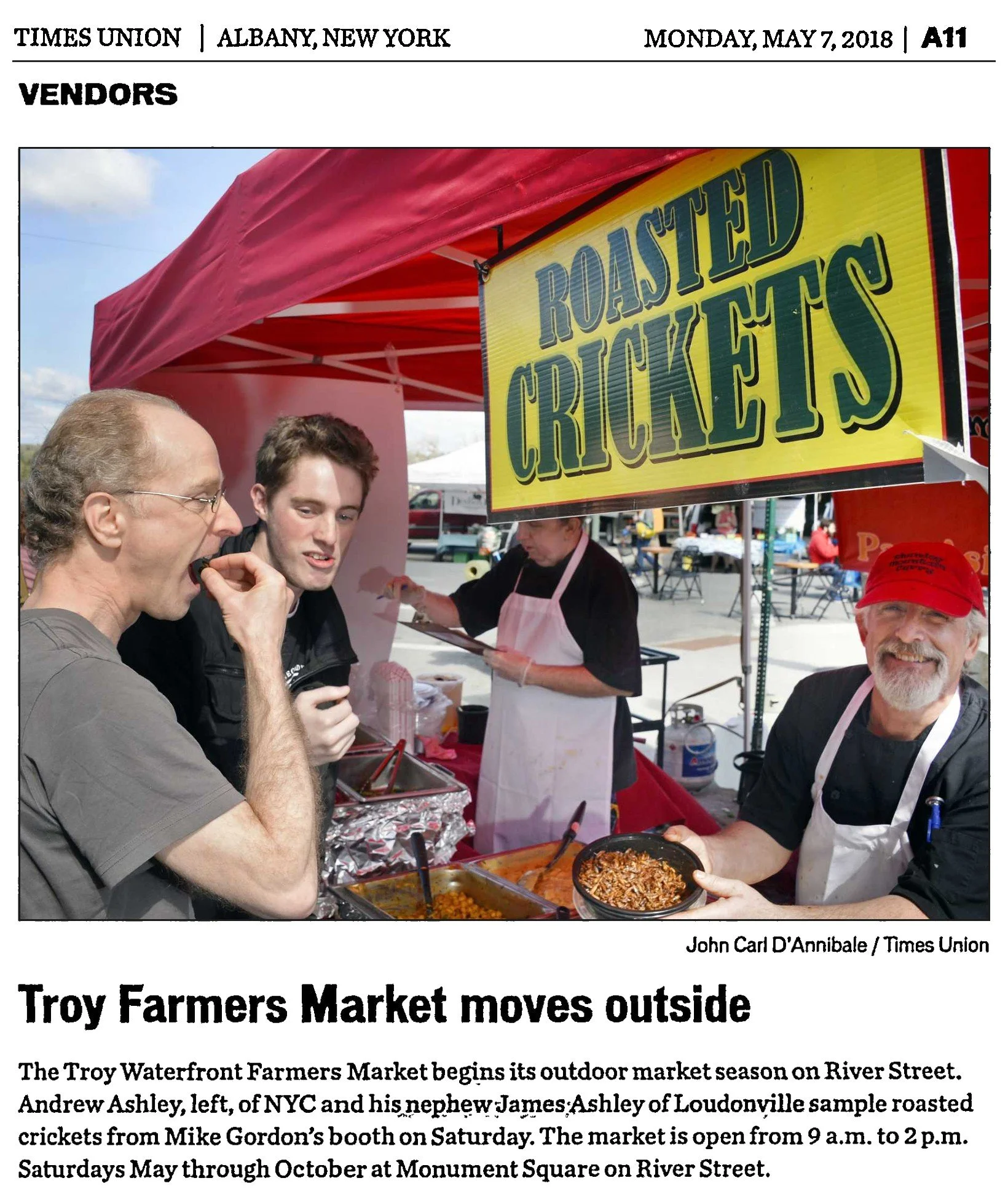 Times Union clipping, Monday, May 7, 2018, page A11: photo “Troy Farmers Market moves outside” by John Carl D’Annibale, showing two shoppers sampling roasted crickets at a vendor’s booth on River Street.