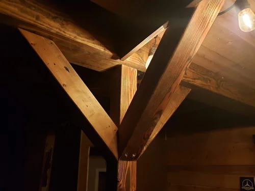 Close-up of wooden beams and ceiling with exposed light bulbs.