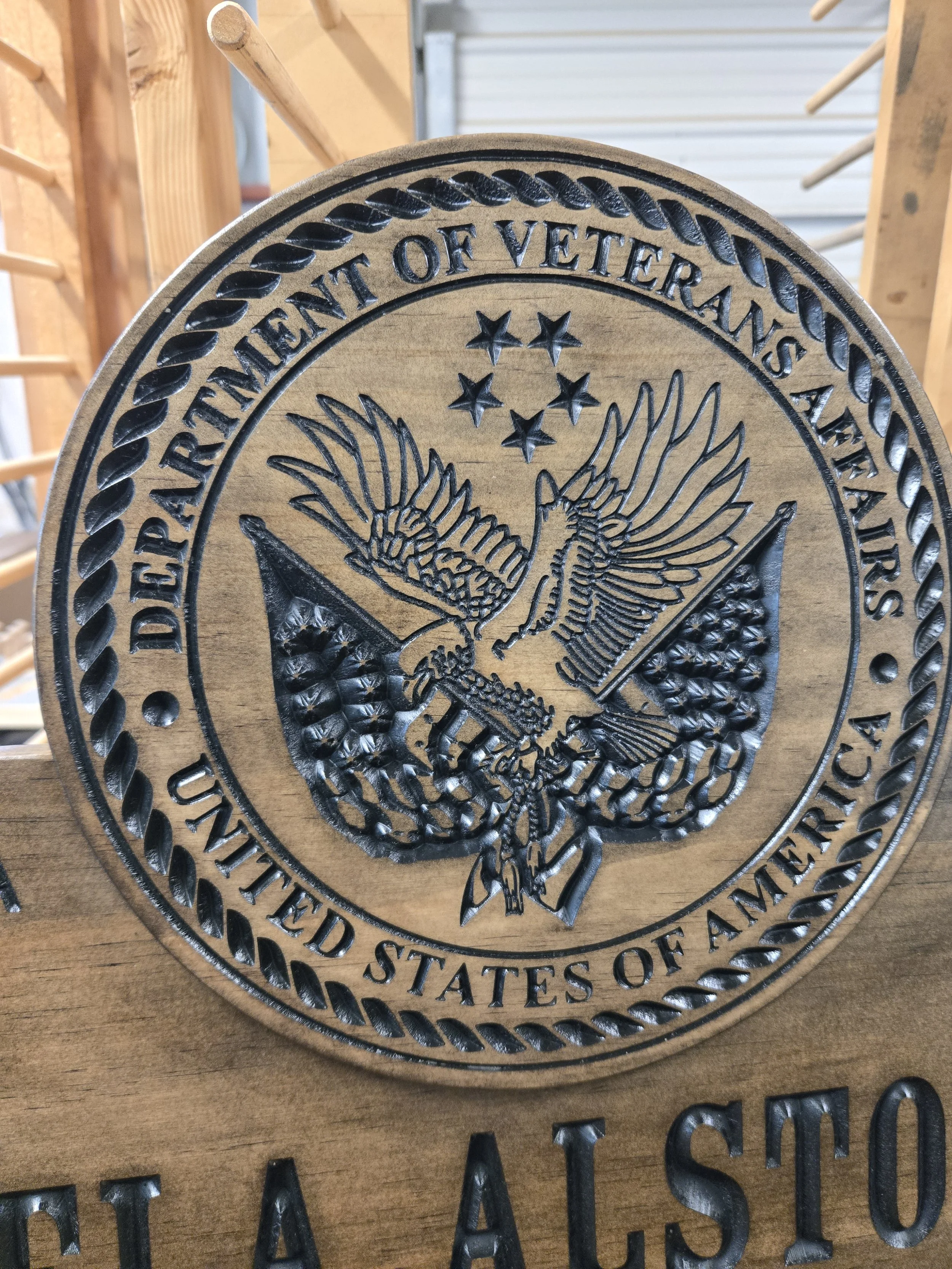 Close-up detail of carved Department of Veterans Affairs emblem on custom military-style retirement plaque showing eagle, stars, and rope border