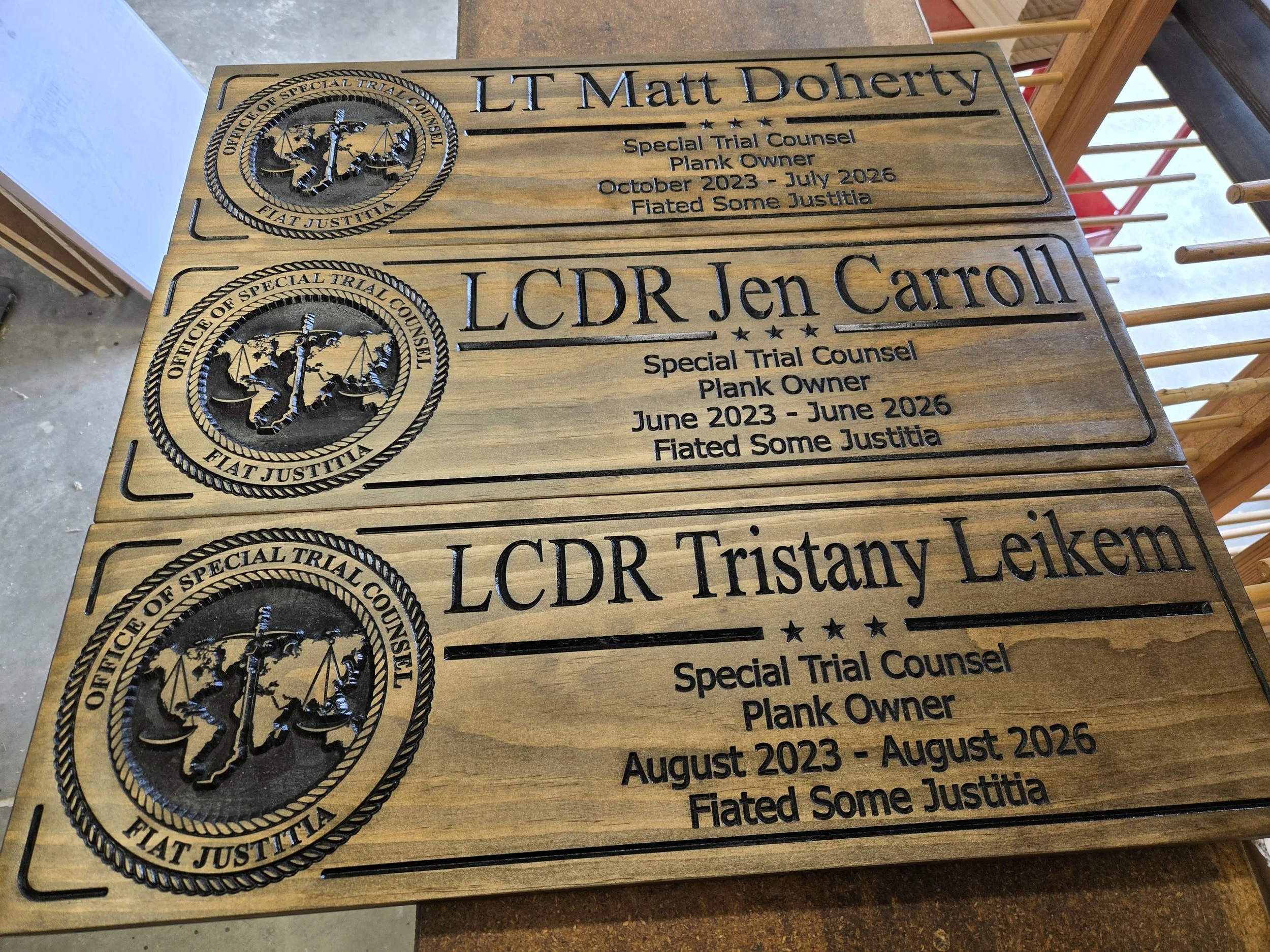 Three carved wooden recognition plaques for Office of Special Trial Counsel officers featuring the official emblem and service details.